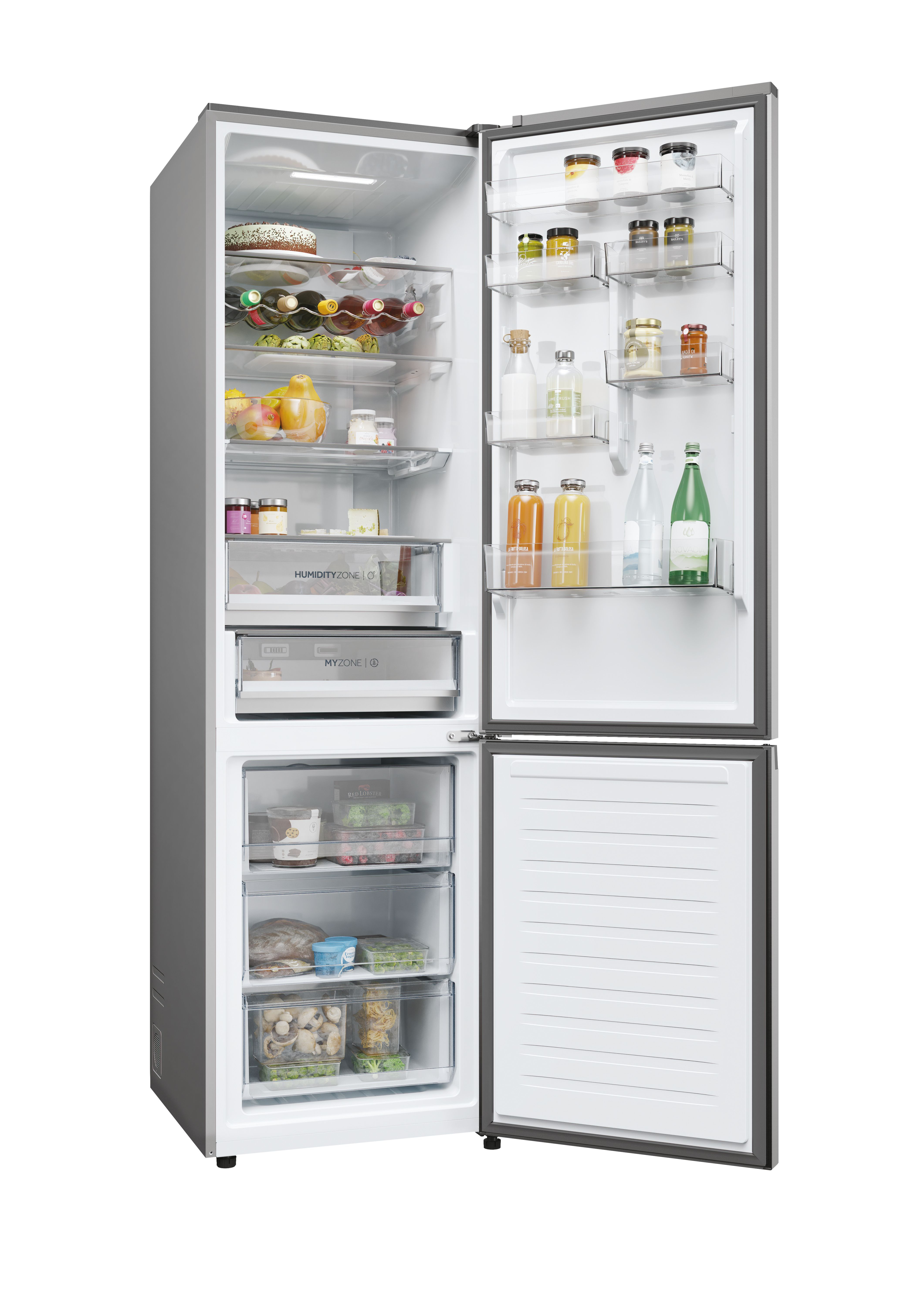 Refrigerador plateado, puertas abiertas, lleno. Estantes superiores: frascos, botellas, pastel. Medio: fruta, zumo. Abajo: cajones, comida.