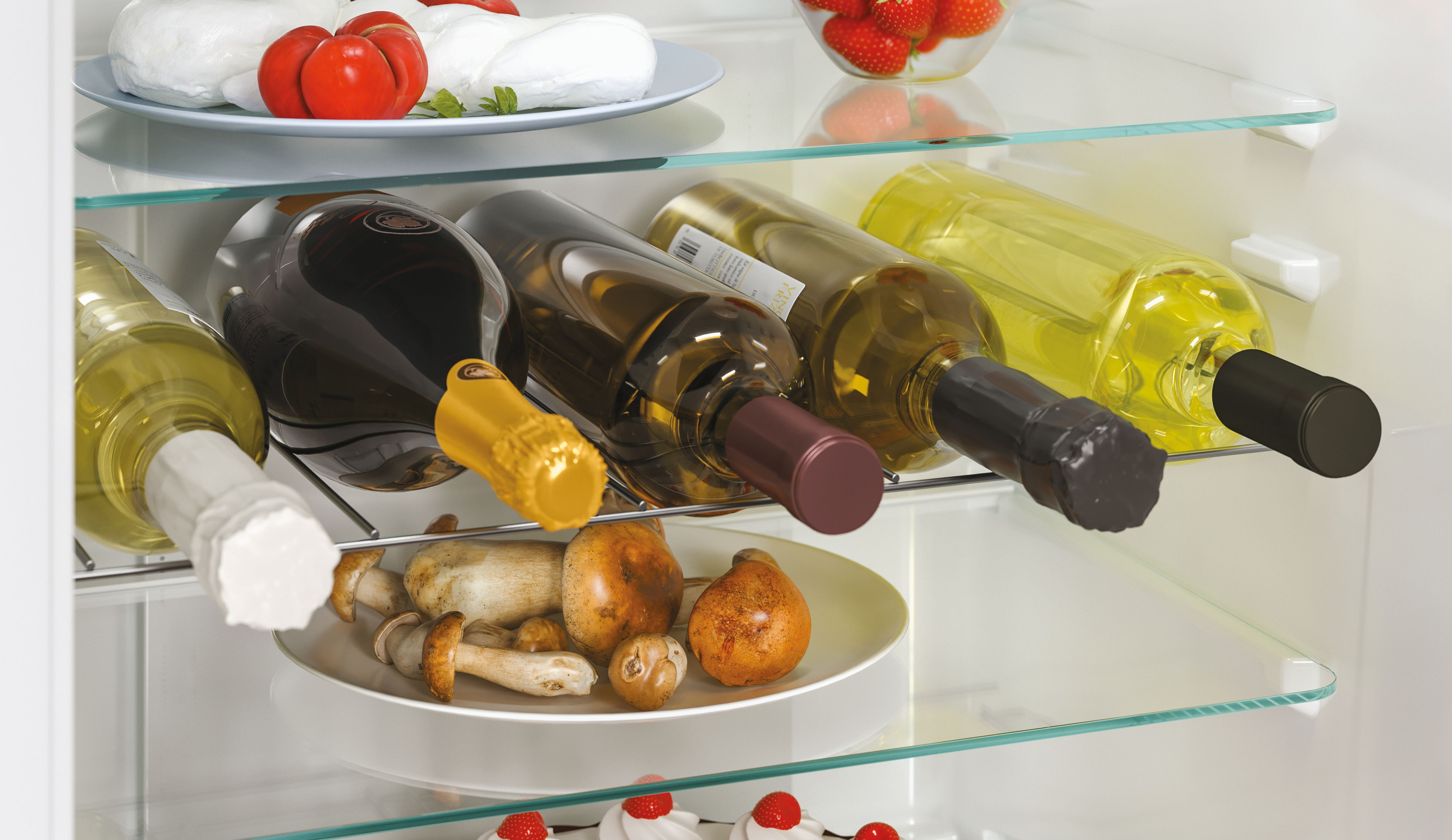 Interno del frigorifero con diverse bottiglie di vino, pomodori, fragole e funghi sugli scaffali. Ripiani in vetro trasparente.