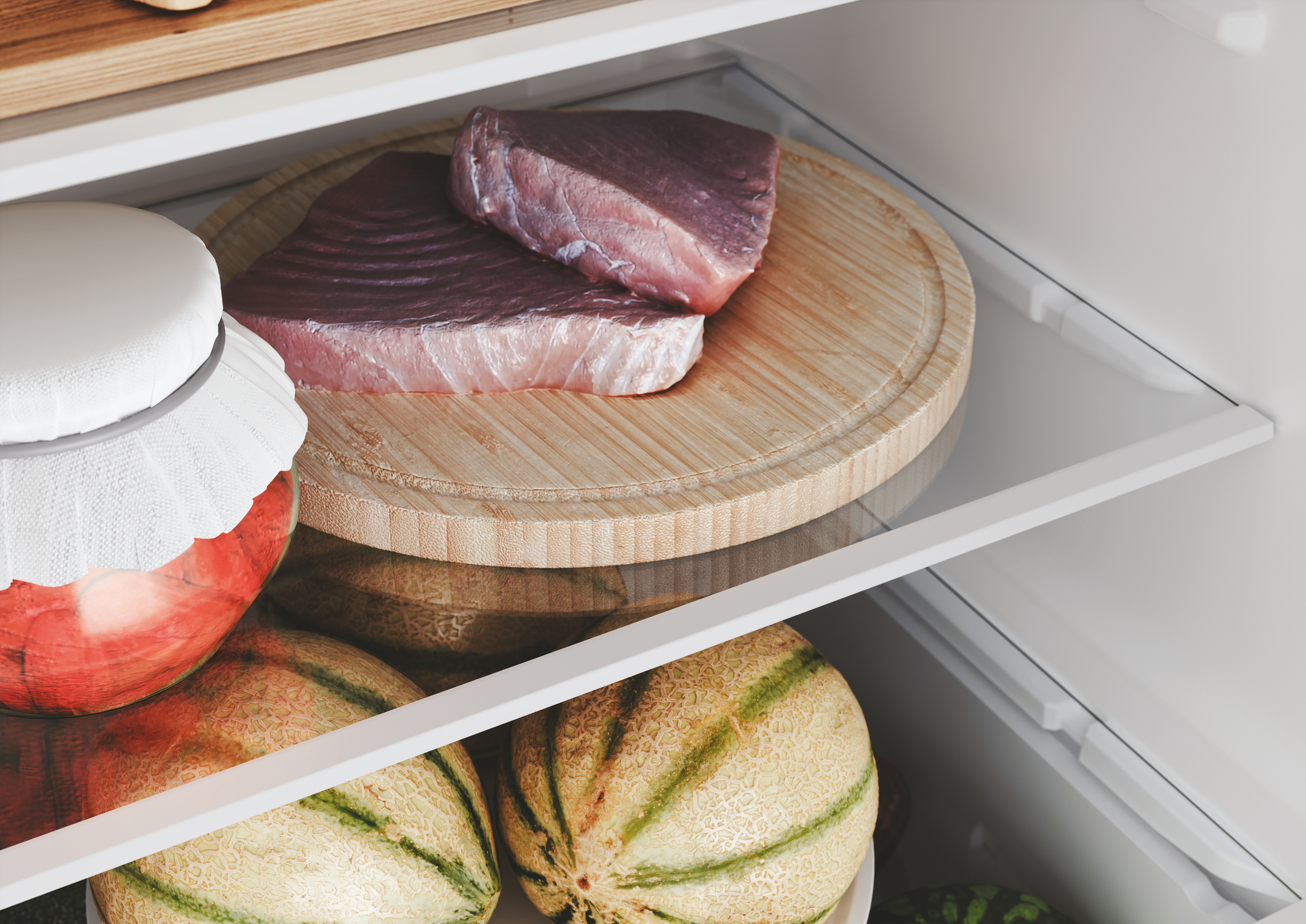 All'interno di un frigorifero. Due pezzi di carne cruda su un tagliere di legno e alcuni meloni.