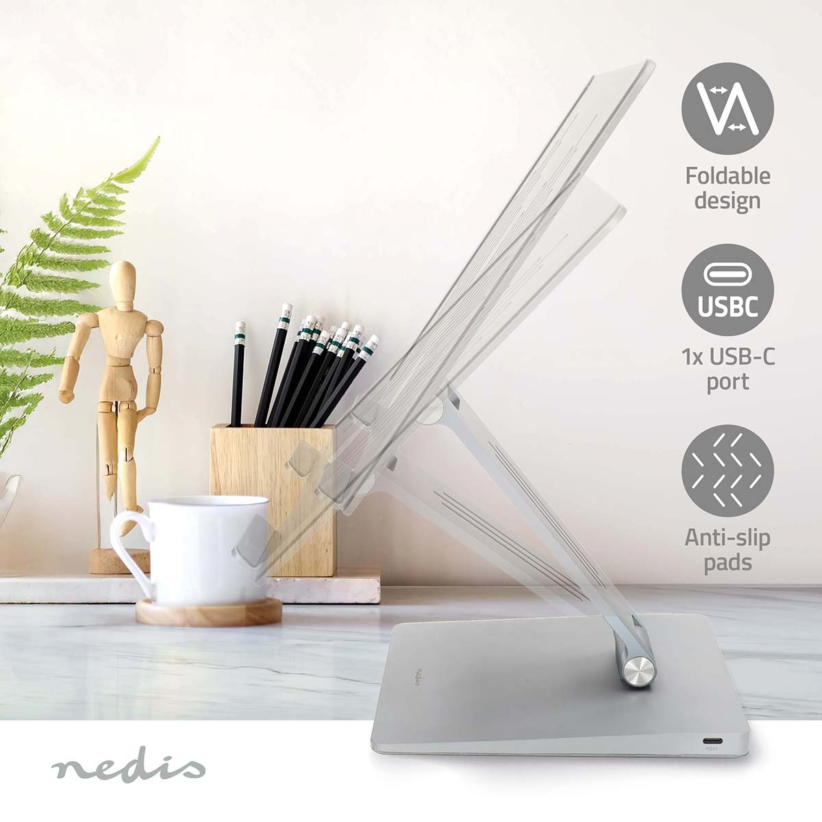 Support pour ordinateur portable avec crayons, une tasse et une figurine en bois sur un bureau. Design pliable, port USB-C et patins antidérapants.