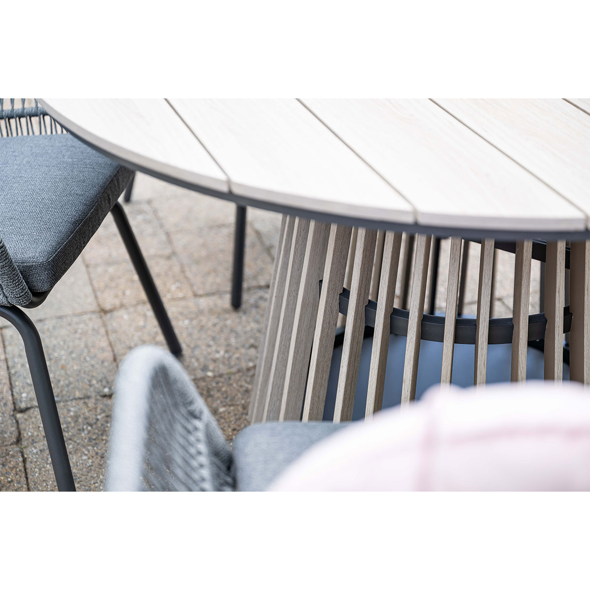 Close-up of a table with chairs. The table has a wooden top and slatted base.