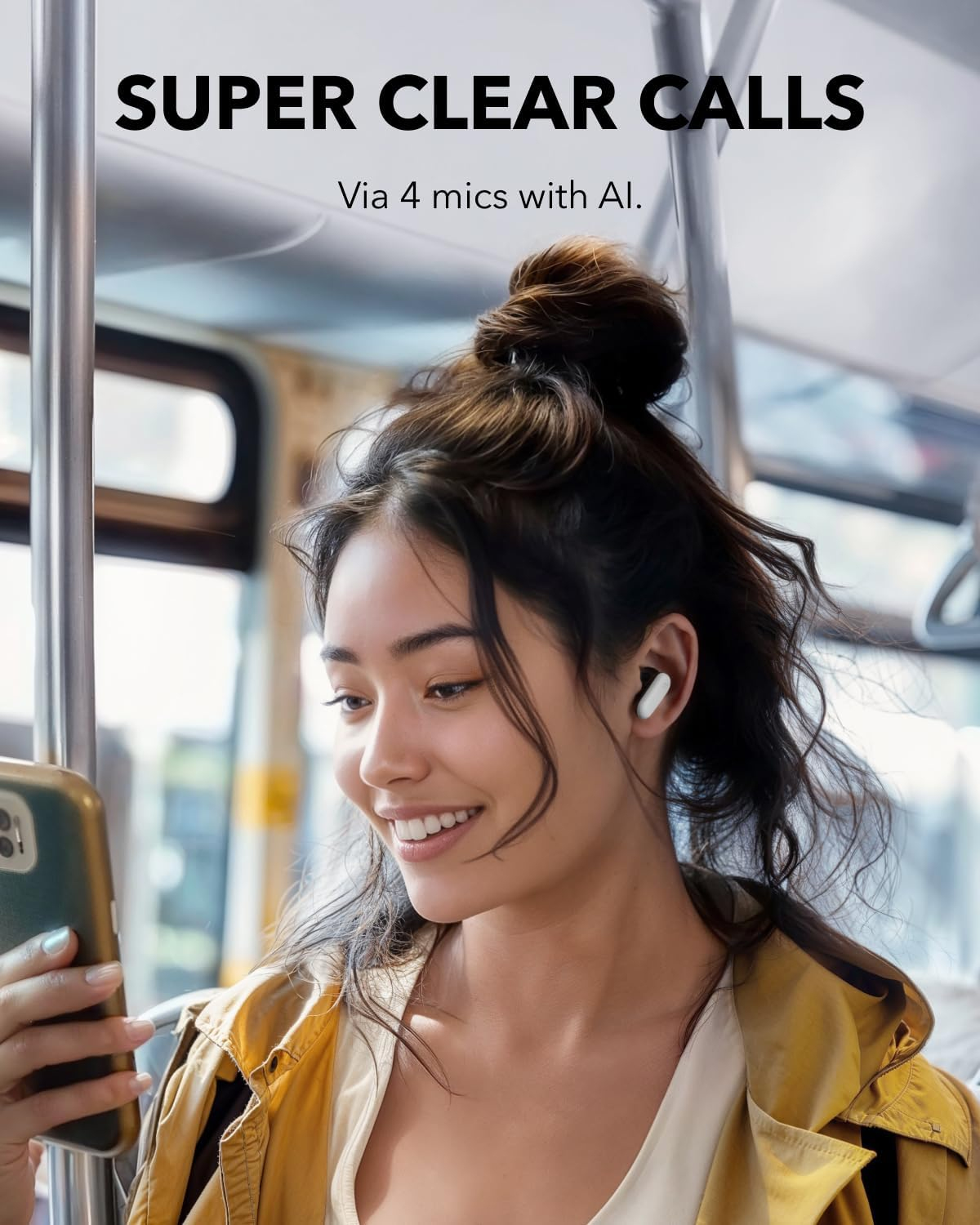 Una mujer sonríe, sosteniendo un teléfono, usando auriculares, en un autobús con fondo borroso.