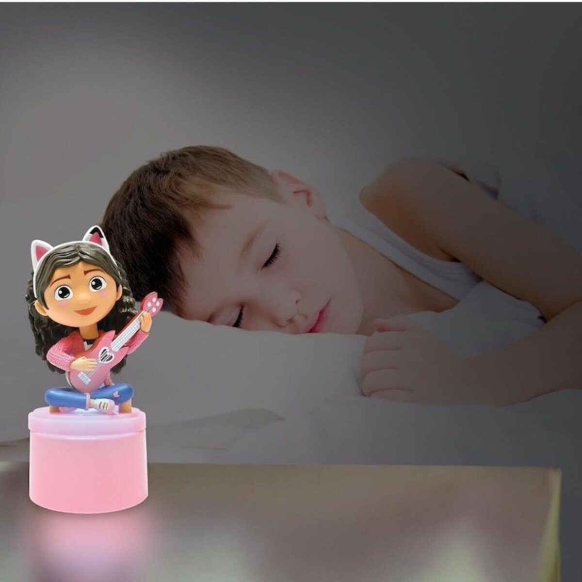 Ein Kind schläft neben einem pinkfarbenen Gabby's Dollhouse Nachtlicht.