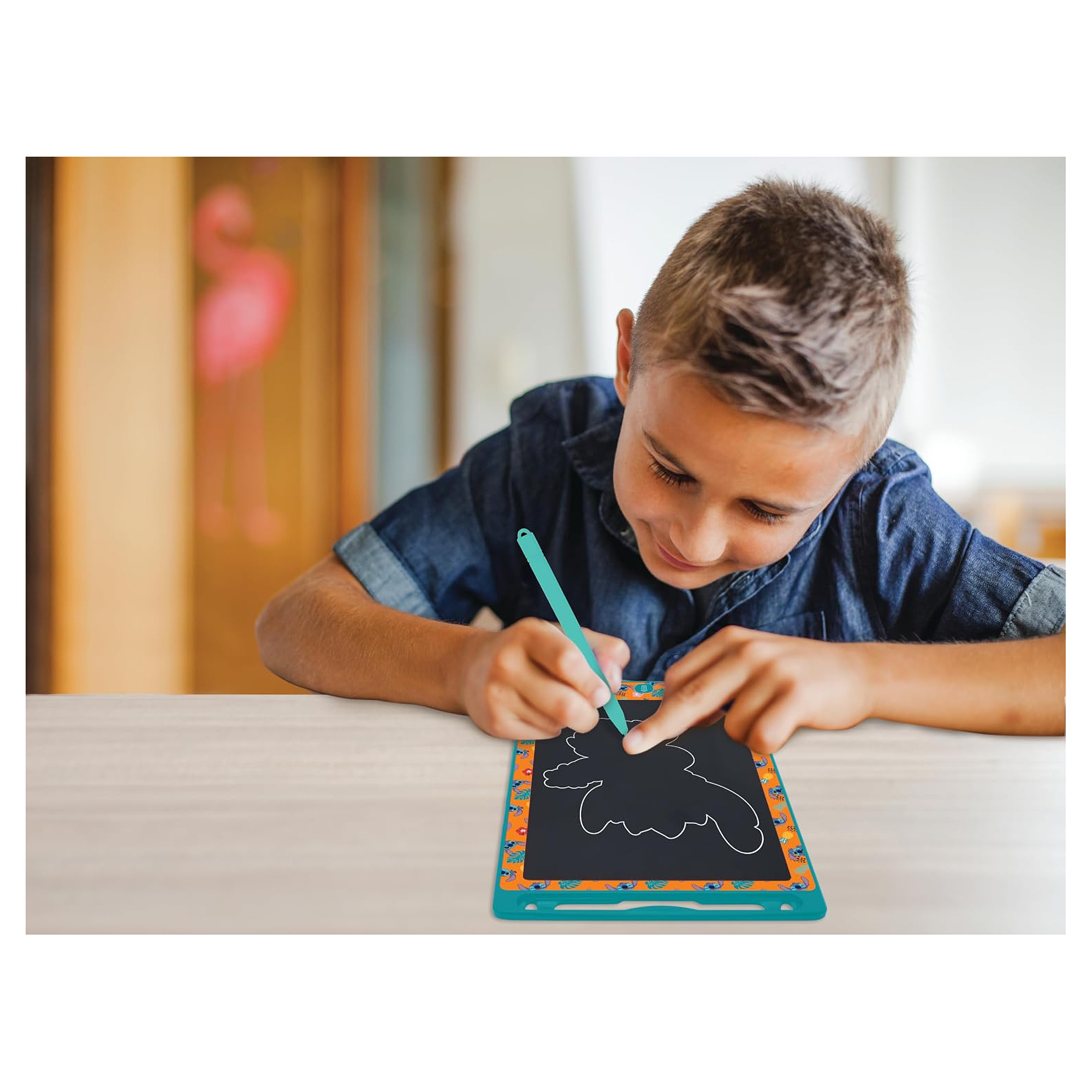 Un niño dibuja en una pizarra de dibujo Stitch azul y naranja con un bolígrafo. El fondo es una habitación.