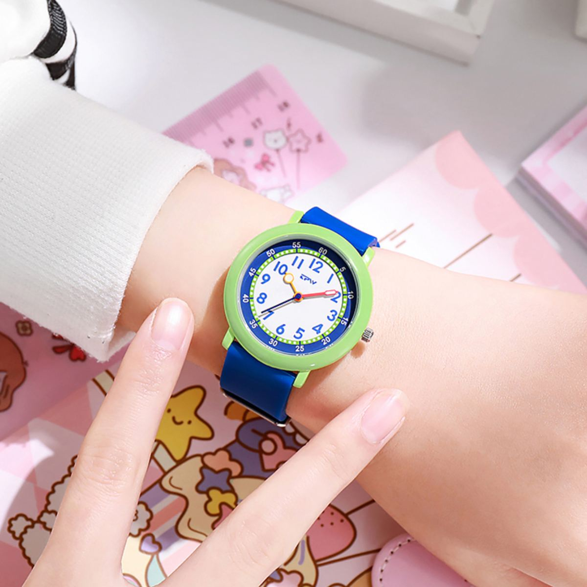 Ein Handgelenk mit einer grün-blauen Uhr. Die Uhr hat weiße Zahlen und rote Zeiger.