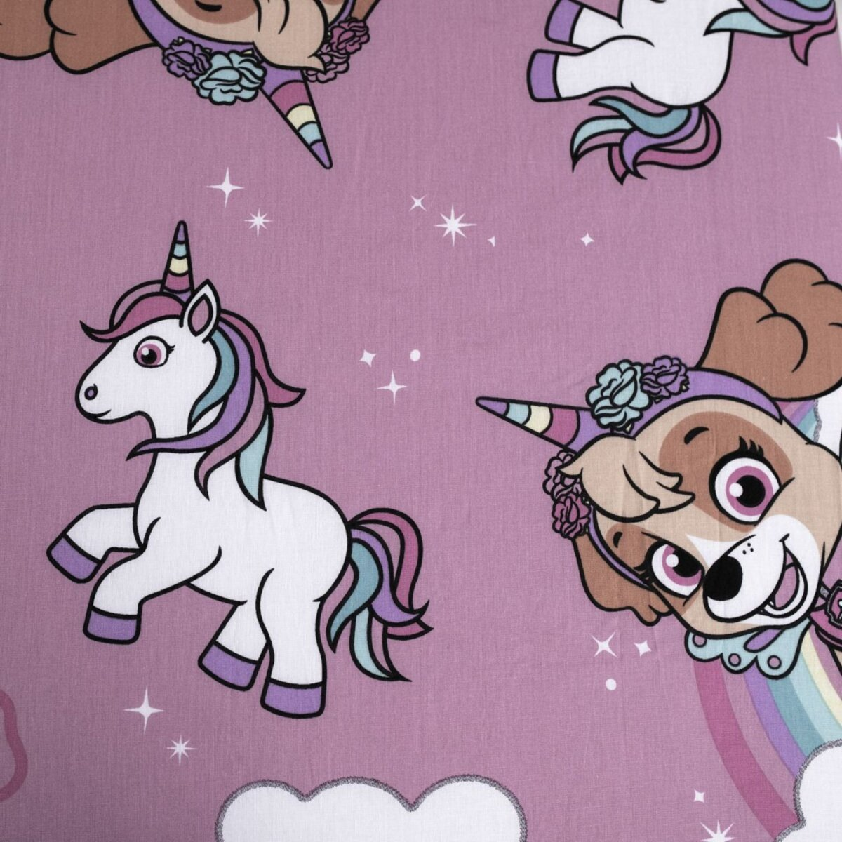 Nahaufnahme eines pinkfarbenen Stoffes mit Cartoon-Einhörnern und -Hunden. Sterne und Wolken sind ebenfalls sichtbar.