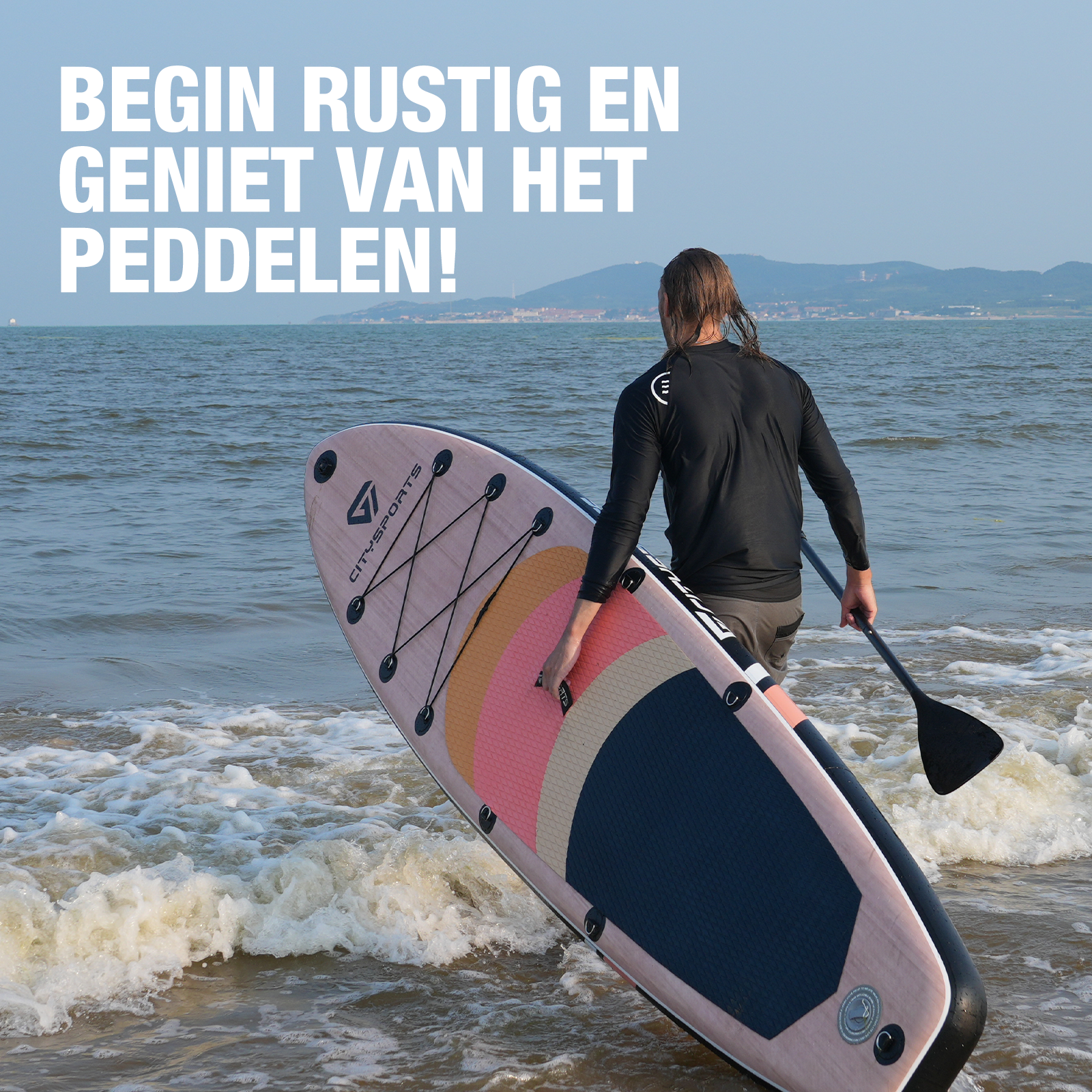 Man die een paddleboard de zee in draagt, met tekst 'BEGIN RUSTIG EN GENIET VAN HET PEDDELEN!'