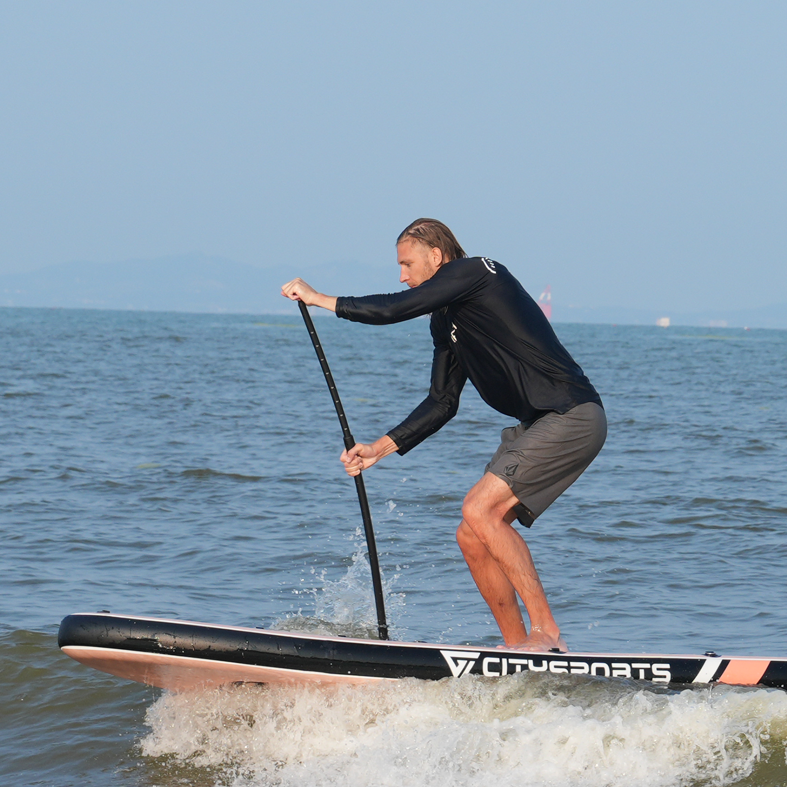 Mężczyzna na desce SUP na morzu, trzymający wiosło, w akcji.
