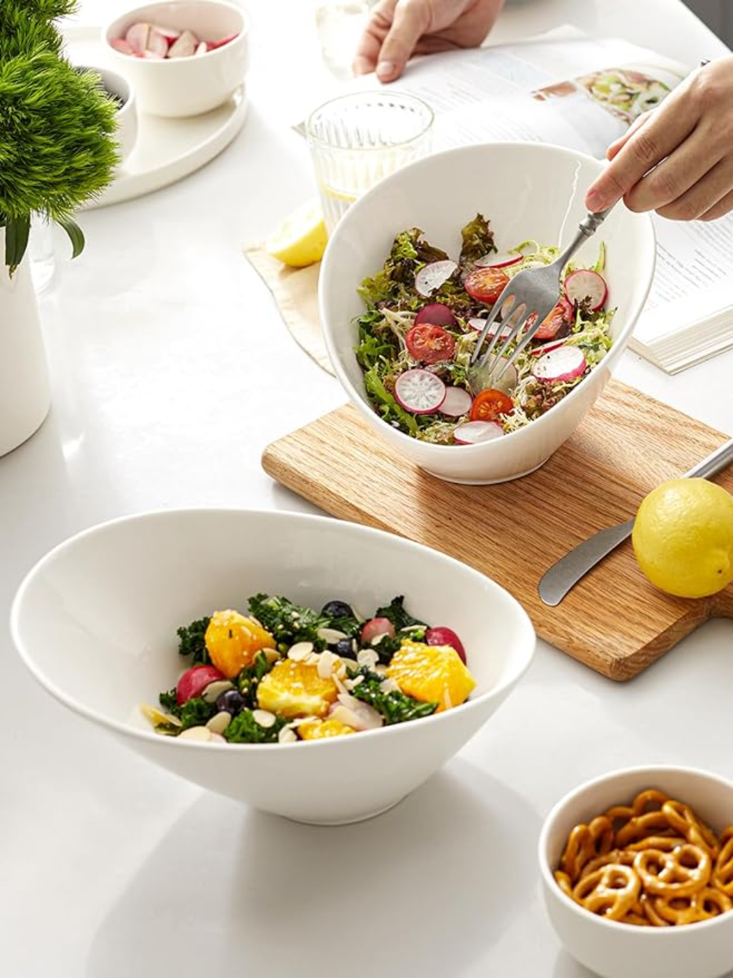 Zwei weiße Schalen mit Essen. Eine Schüssel hat Salat mit Tomaten. Person hält eine Gabel.