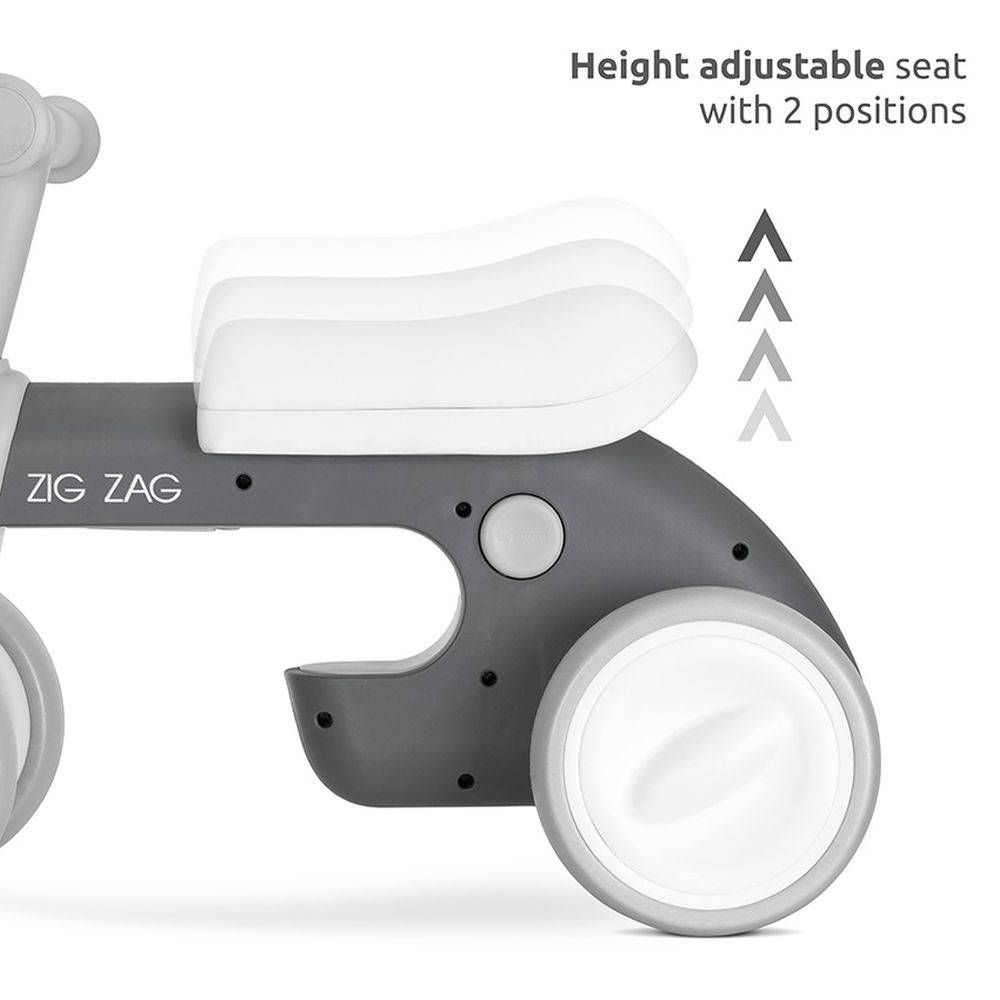 Primer plano del asiento de una bicicleta de equilibrio gris y blanca, mostrando el ajuste de altura.
