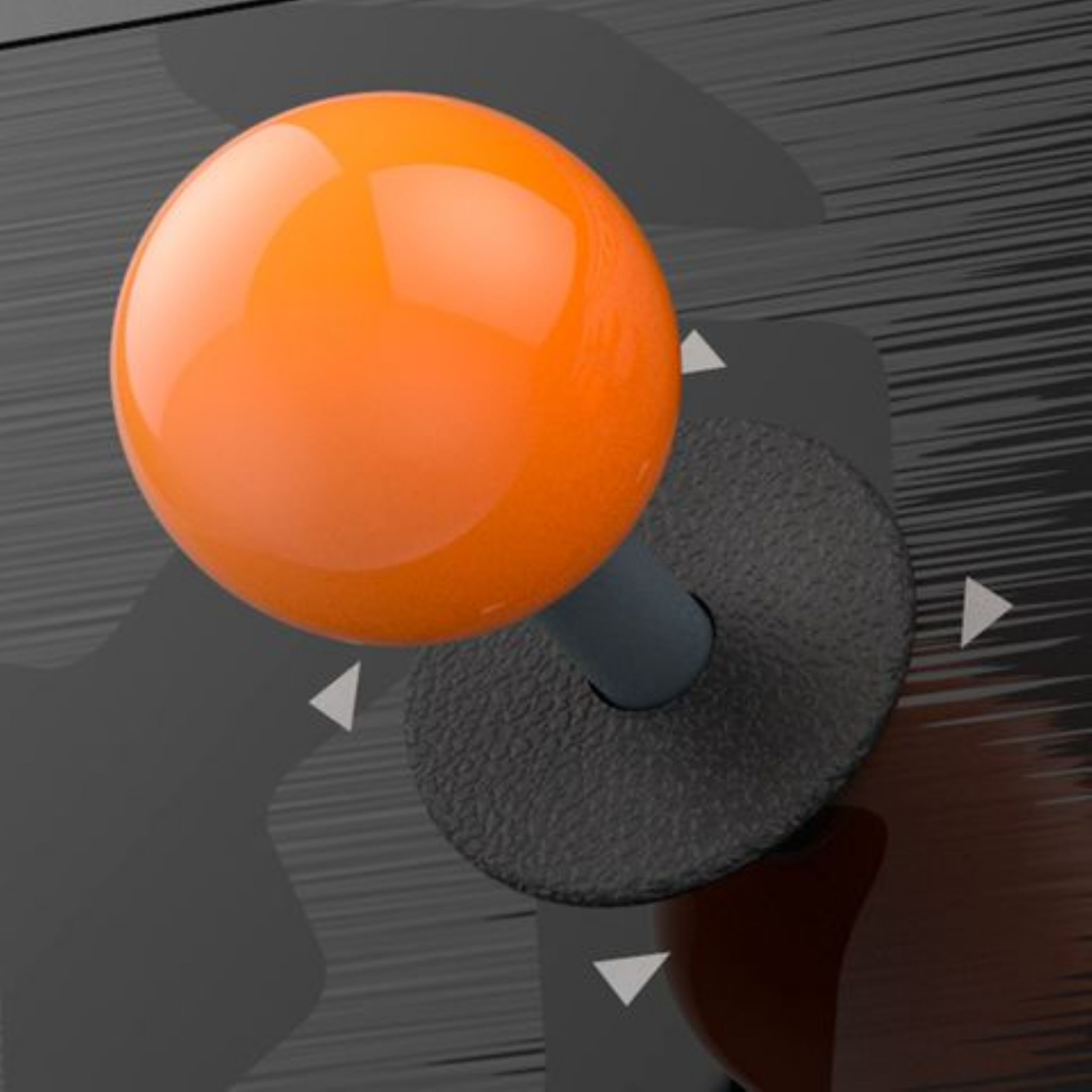 Pomarańczowy joystick na czarnej podstawie. Tło to ciemna, teksturowana powierzchnia.