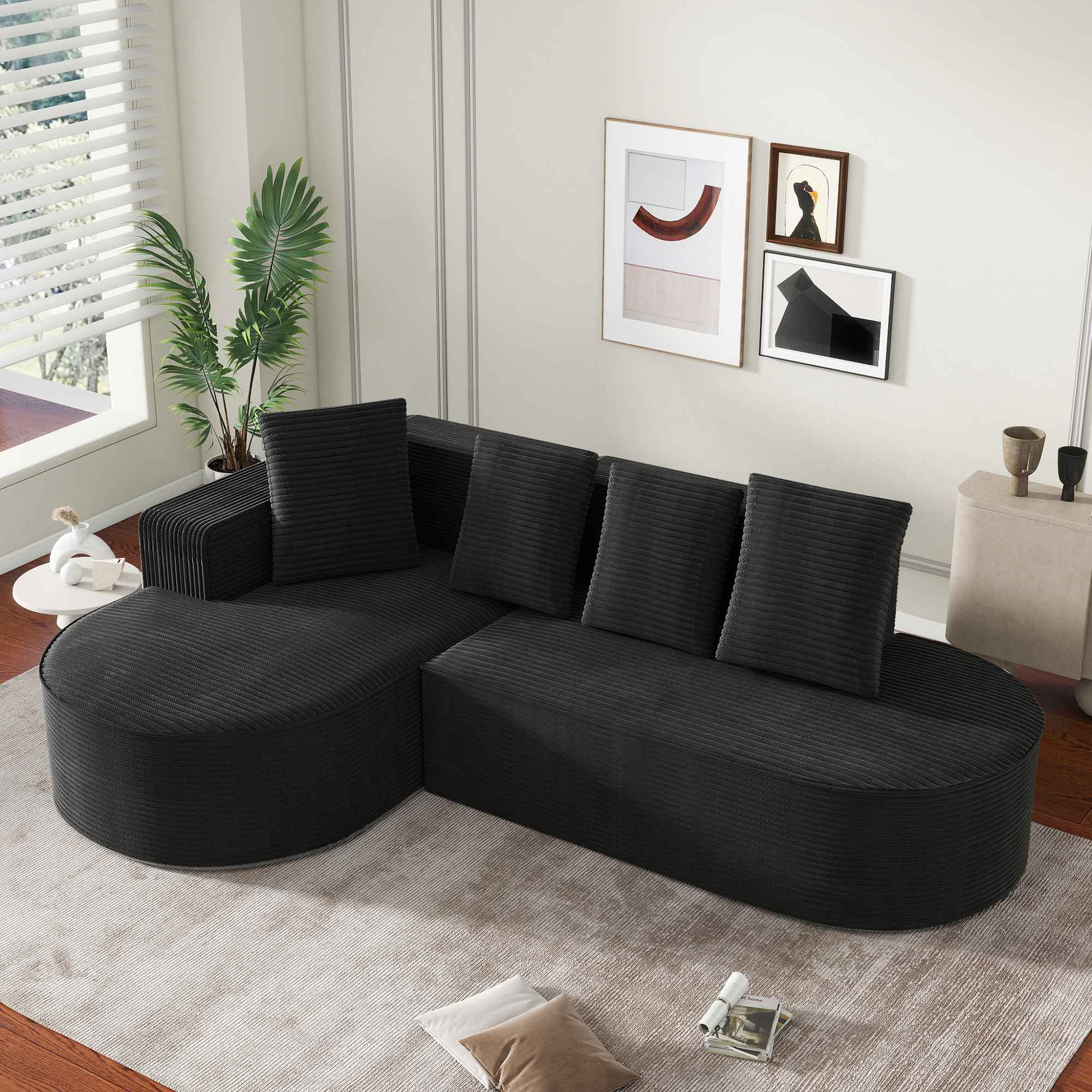Ein schwarzes Ecksofa in einem Raum. Das Sofa hat ein geschwungenes Design. An der Wand hängen Bilder.