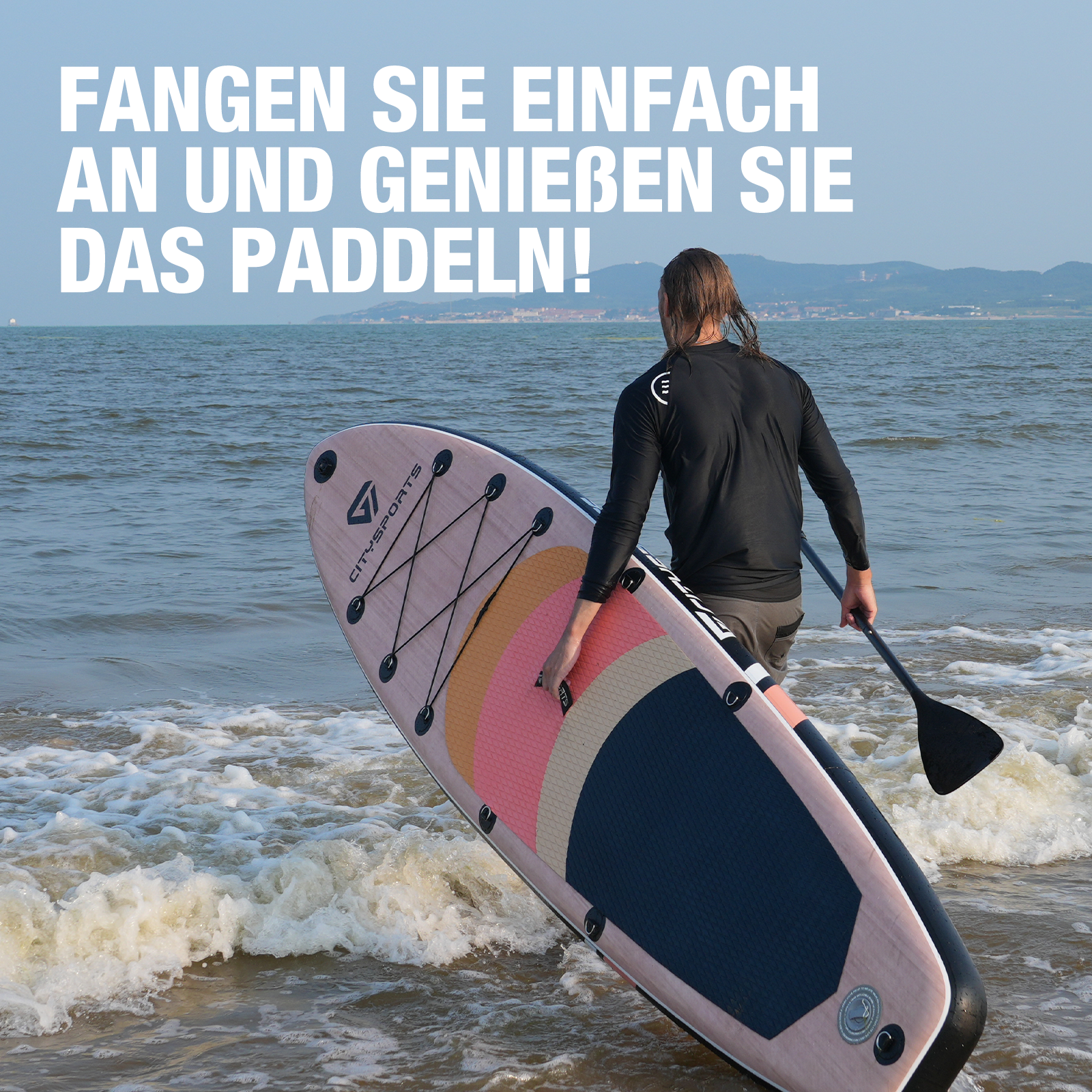 Un homme est vu portant un paddleboard de l'eau à la plage, une pagaie à la main.