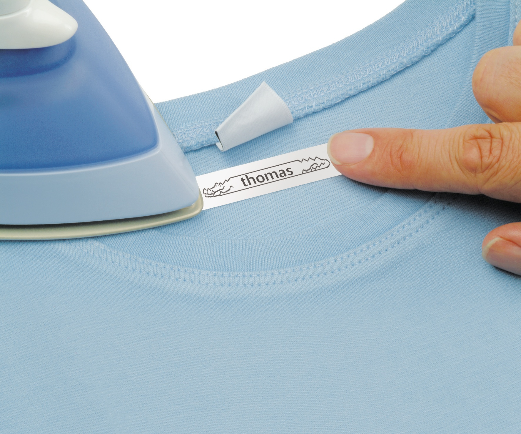 Osoba prasująca etykietę na błękitnej koszuli z imieniem 'thomas'.
