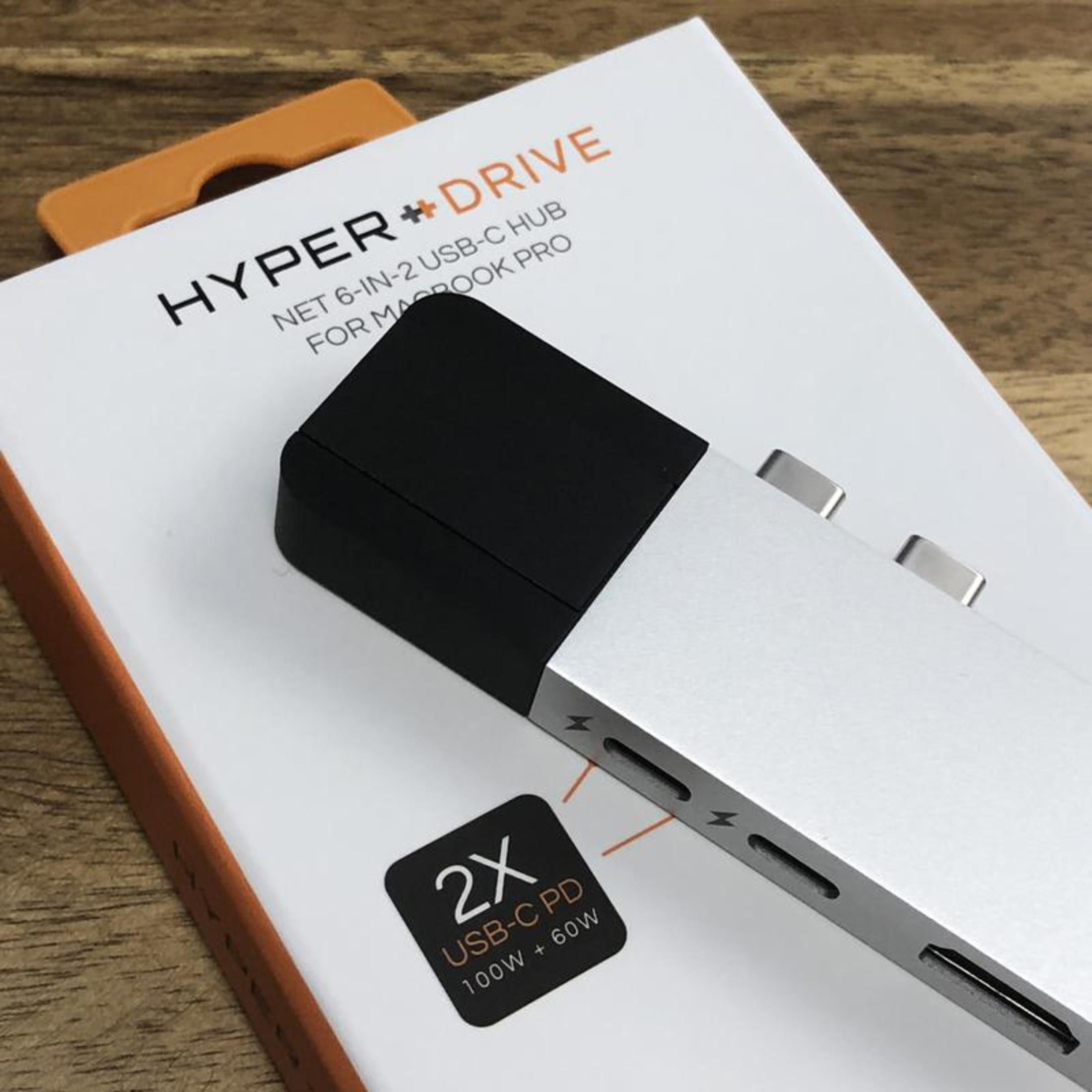 Un hub USB-C per MacBook Pro è su una scatola bianca, con un hub argentato. La scatola ha il logo Hyper + Drive.