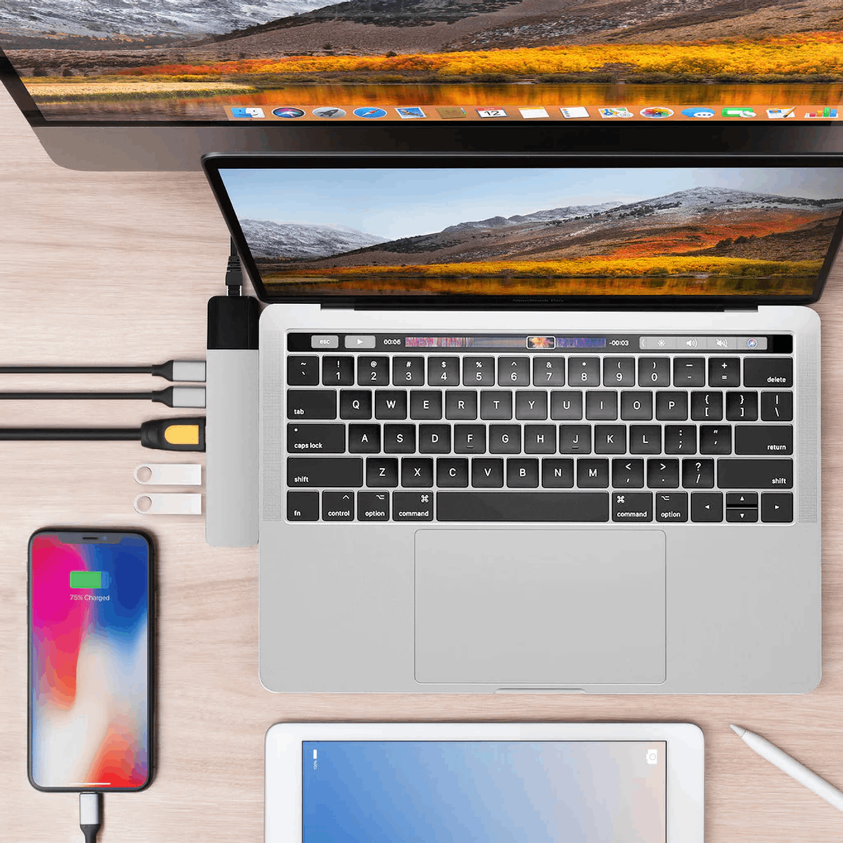 Configurazione laptop, telefono, tablet e hub USB, su una scrivania di legno, con cavi.