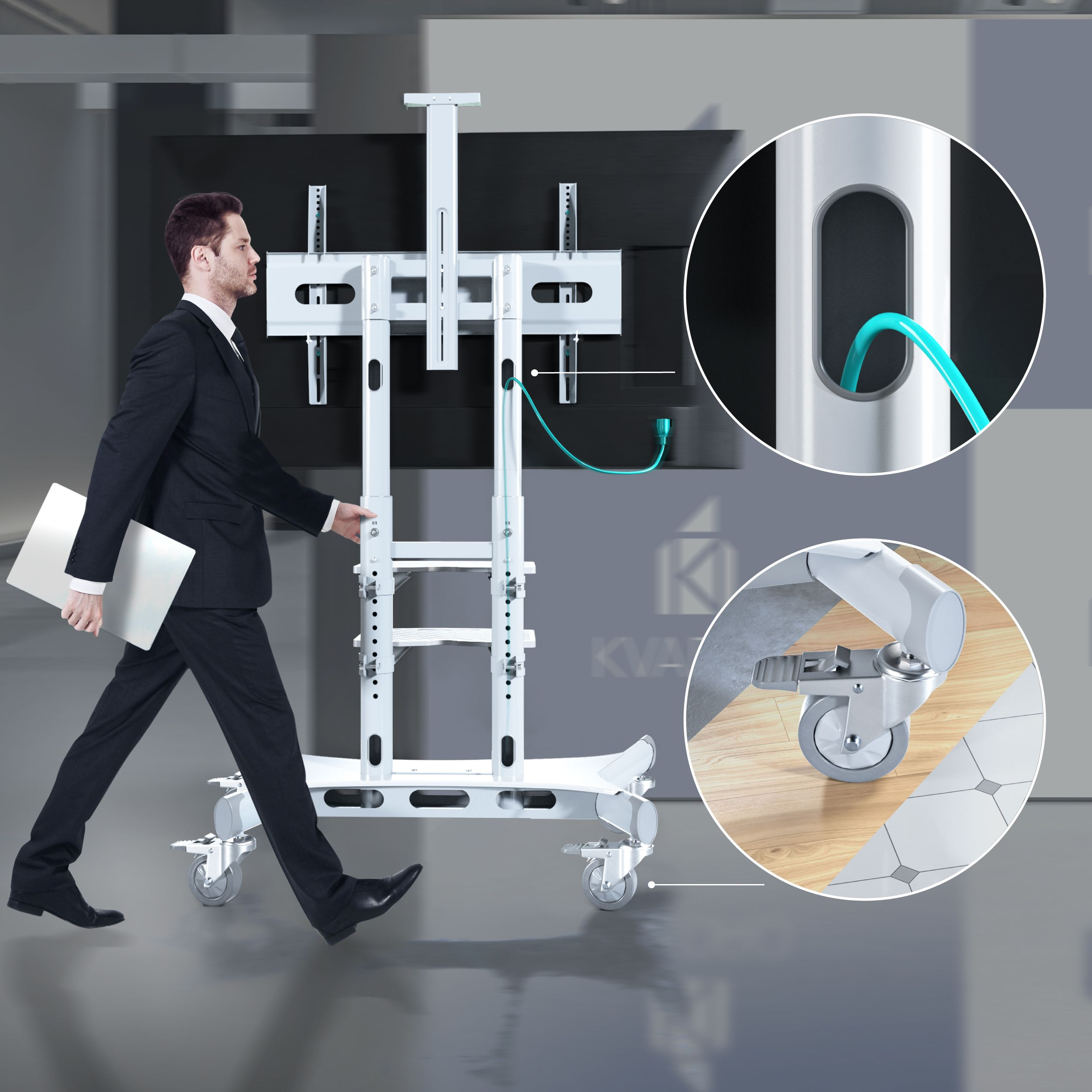 Mężczyzna w garniturze idzie, pchając mobilny stojak pod telewizor. Widzimy zbliżenie kół i szczegół kabla.