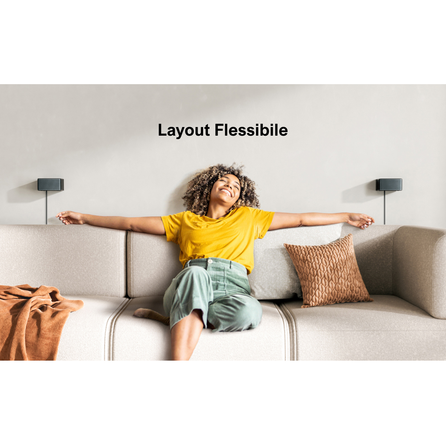 Una donna con le braccia distese siede su un divano, con una coperta e cuscini marroni, promuovendo un layout flessibile.