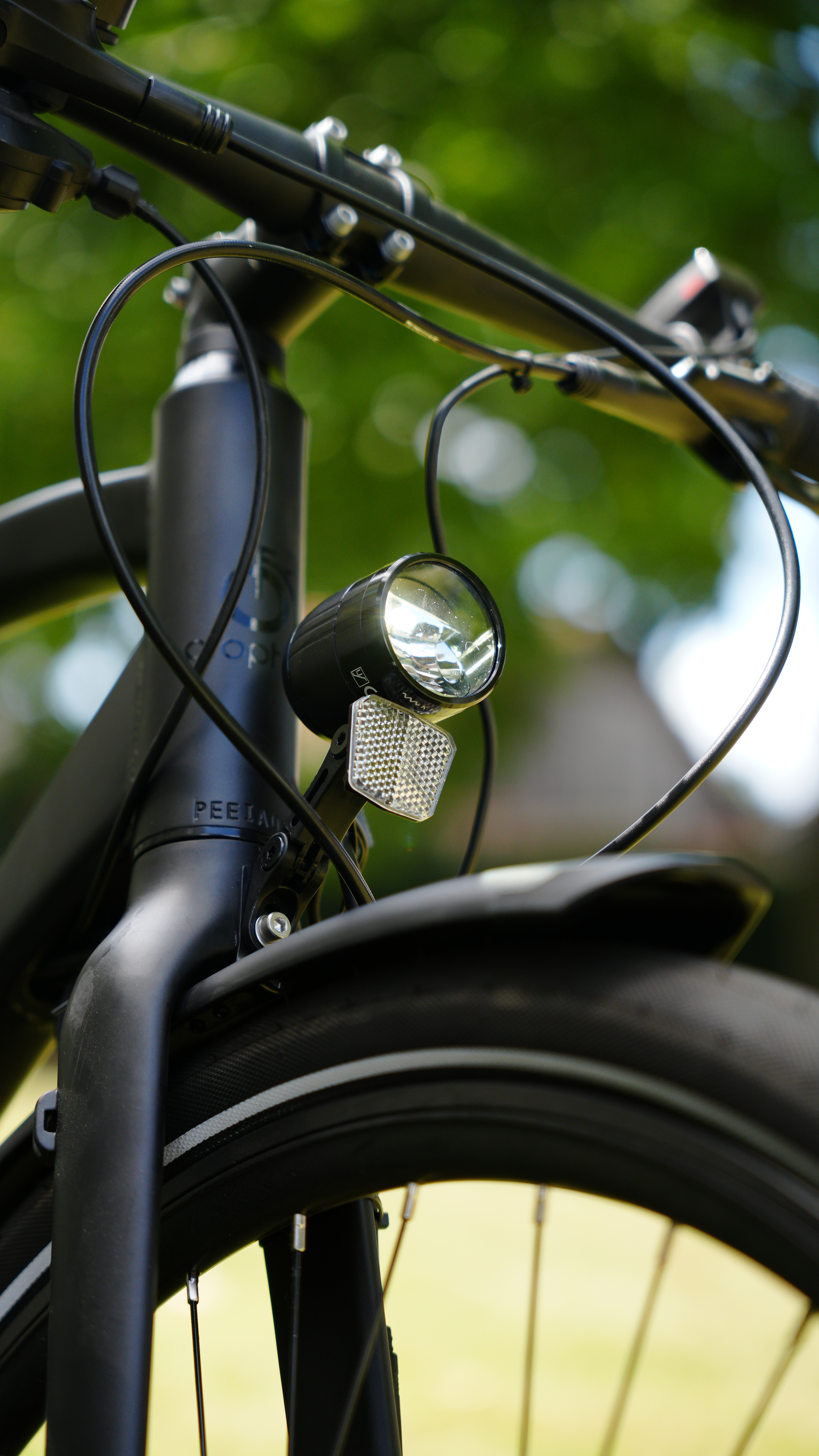 Nahaufnahme der Vorderseite eines schwarzen Fahrrads mit Scheinwerfer, Reflektor und Lenker.