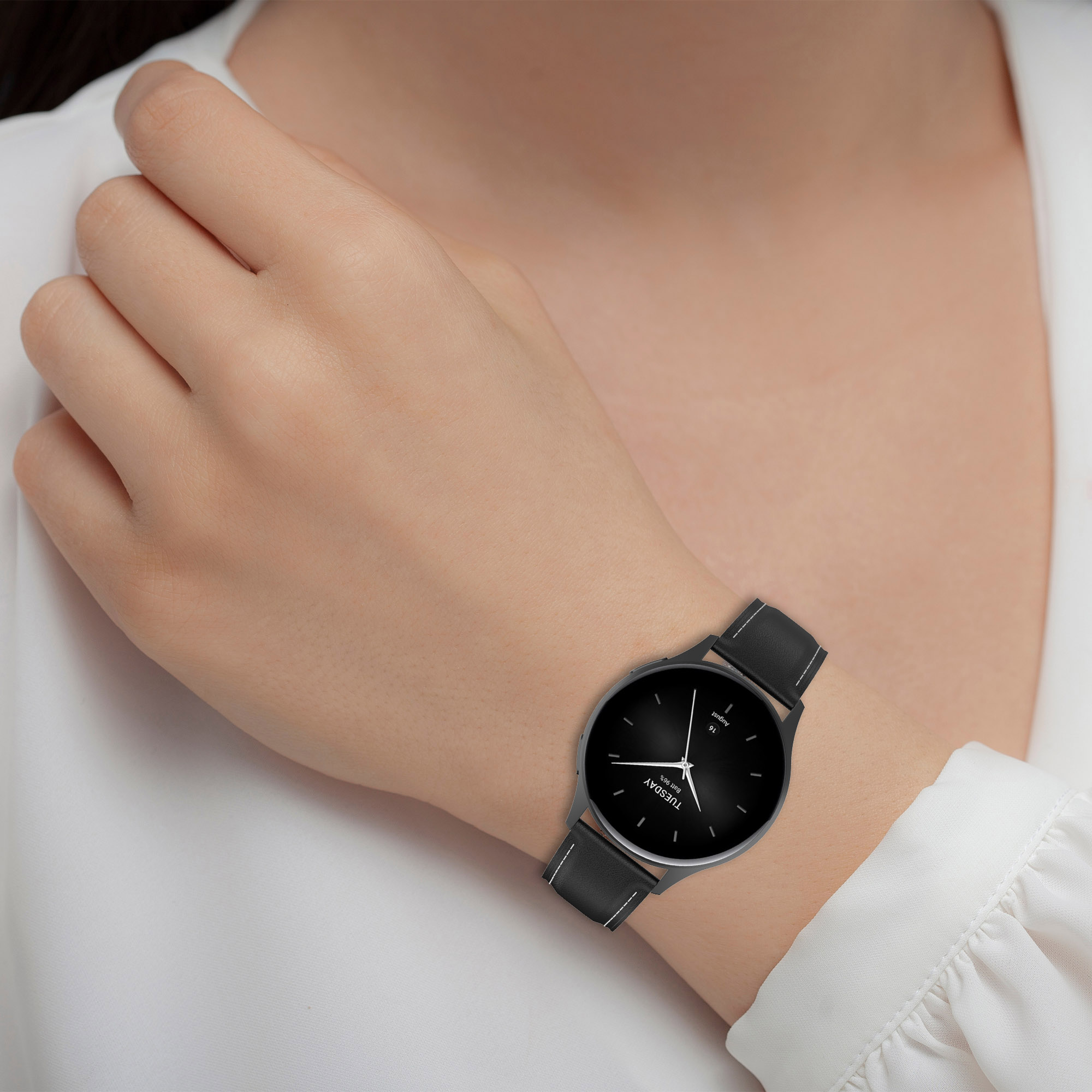 Das Handgelenk einer Person mit einer schwarzen Uhr und schwarzem Armband.