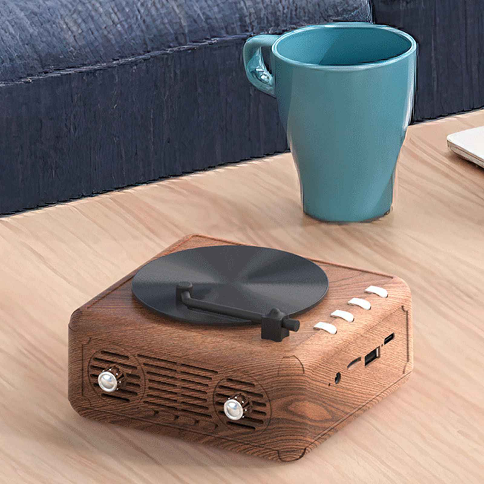 Ein hölzerner Plattenspieler mit schwarzem Plattenteller und Bedienelementen, auf einem Holztisch platziert. Daneben eine blaue Tasse.