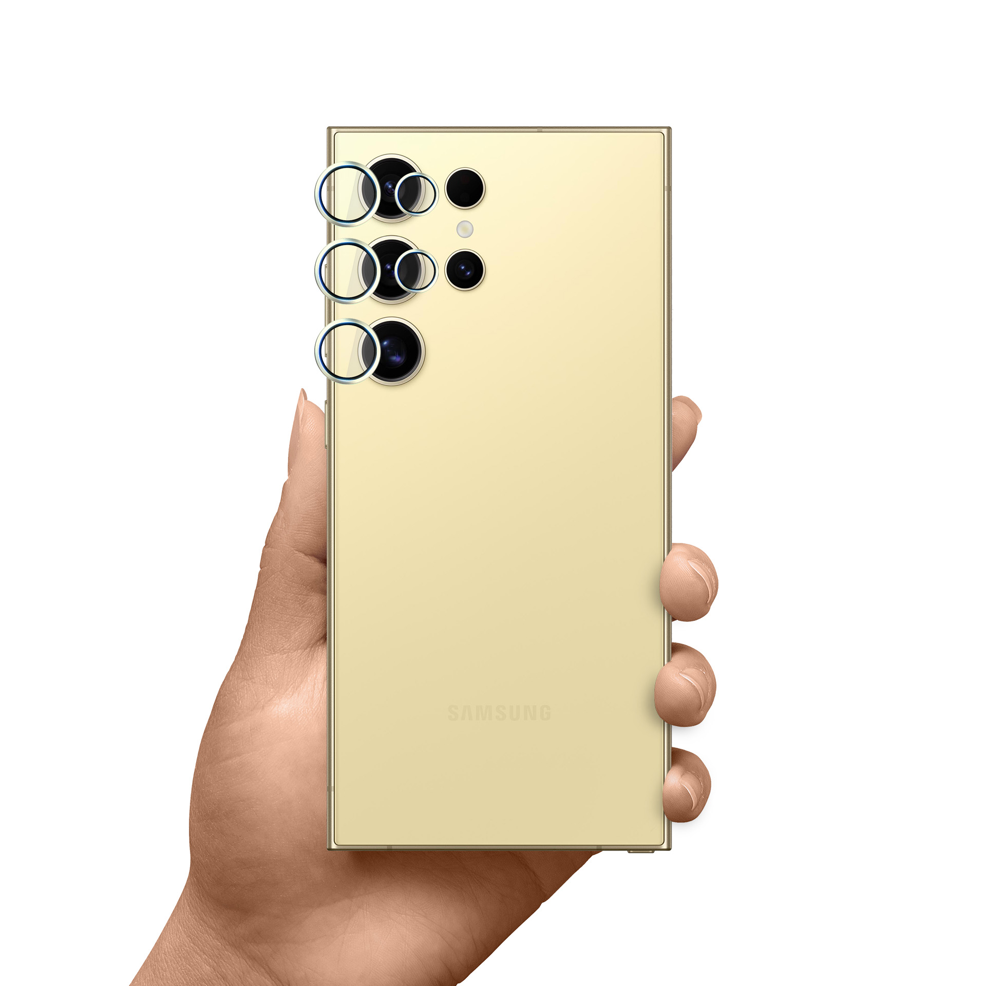 Una mano tiene un telefono dorato con tre anelli per fotocamera e altre fotocamere. Sfondo bianco.
