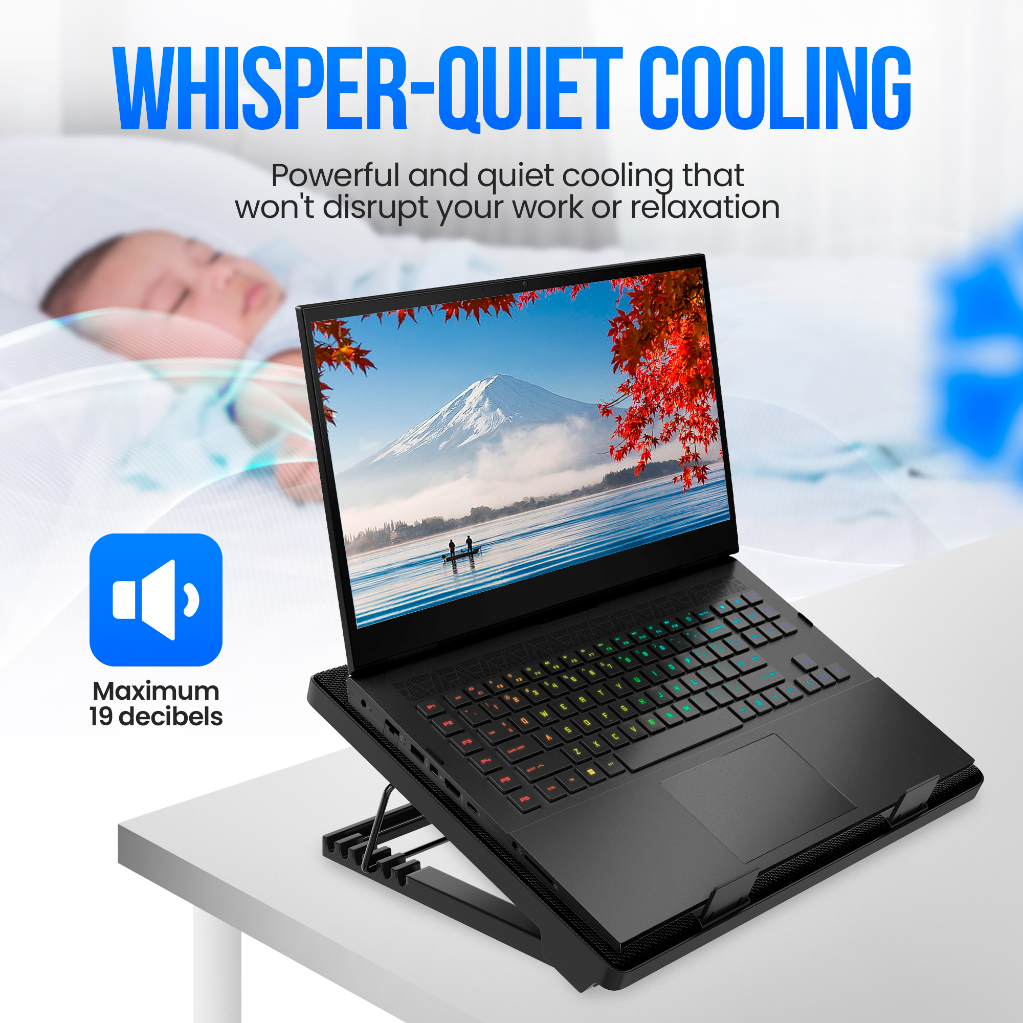 Een laptop staat op een koeler met een slapende baby op de achtergrond. Het scherm toont een berglandschap.