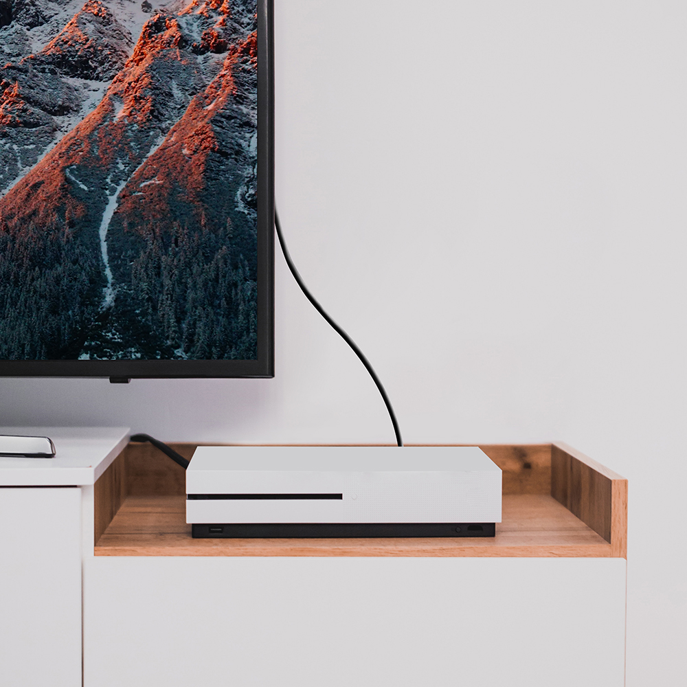 Una consola blanca en un estante de madera, conectada a un televisor, con un fondo neutro.