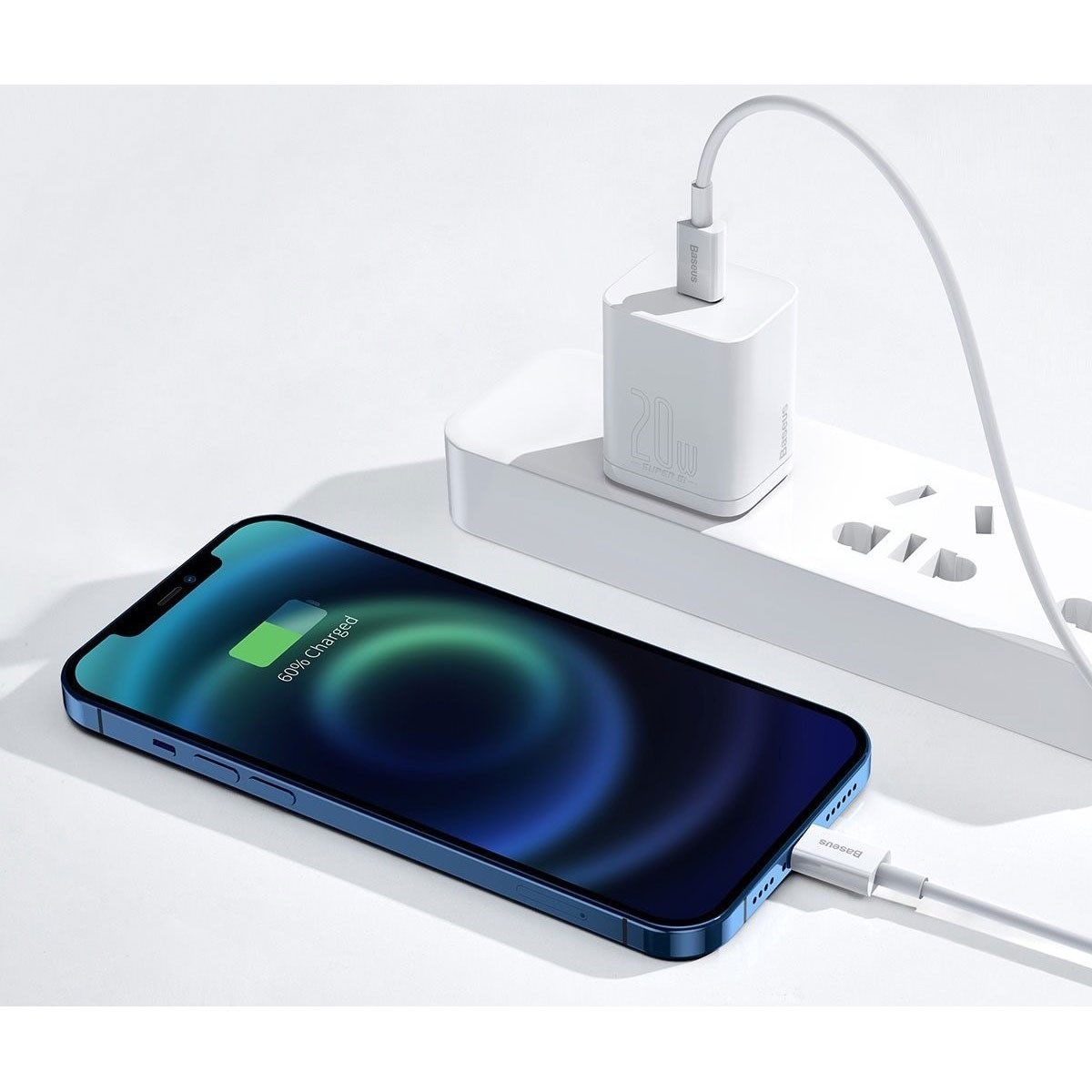 Uno smartphone in carica con un caricatore bianco collegato a una presa a muro. Il telefono è blu.