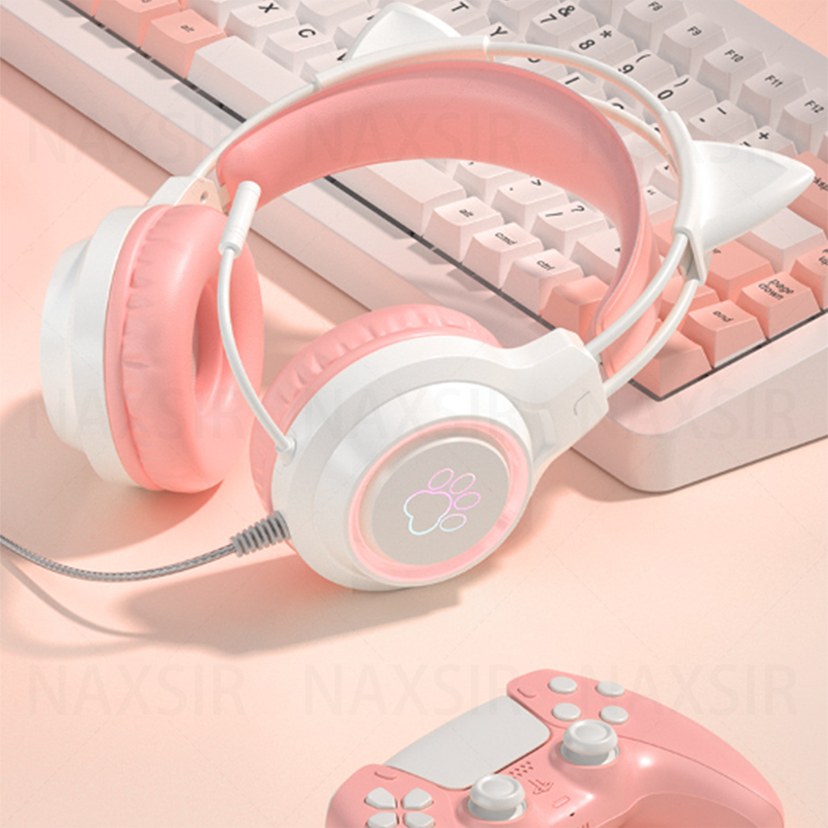 Rosa Katzenohr-Kopfhörer auf einem Schreibtisch mit Tastatur und Controller. Rosa Hintergrund.