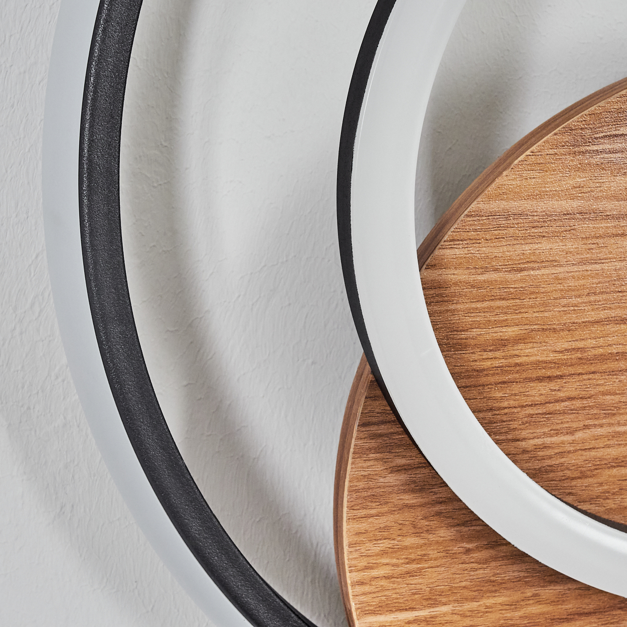 Nahaufnahme einer modernen Wandleuchte mit konzentrischen Ringen und Holzakzenten, die ihre Designdetails zeigt.