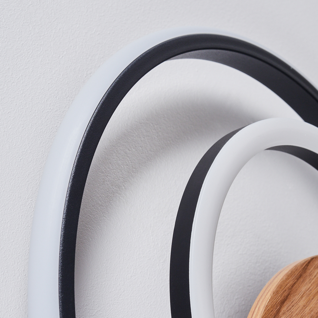 Nahaufnahme einer modernen Wandleuchte mit konzentrischen Ringen und Holzakzenten, die ihre Designdetails zeigt.