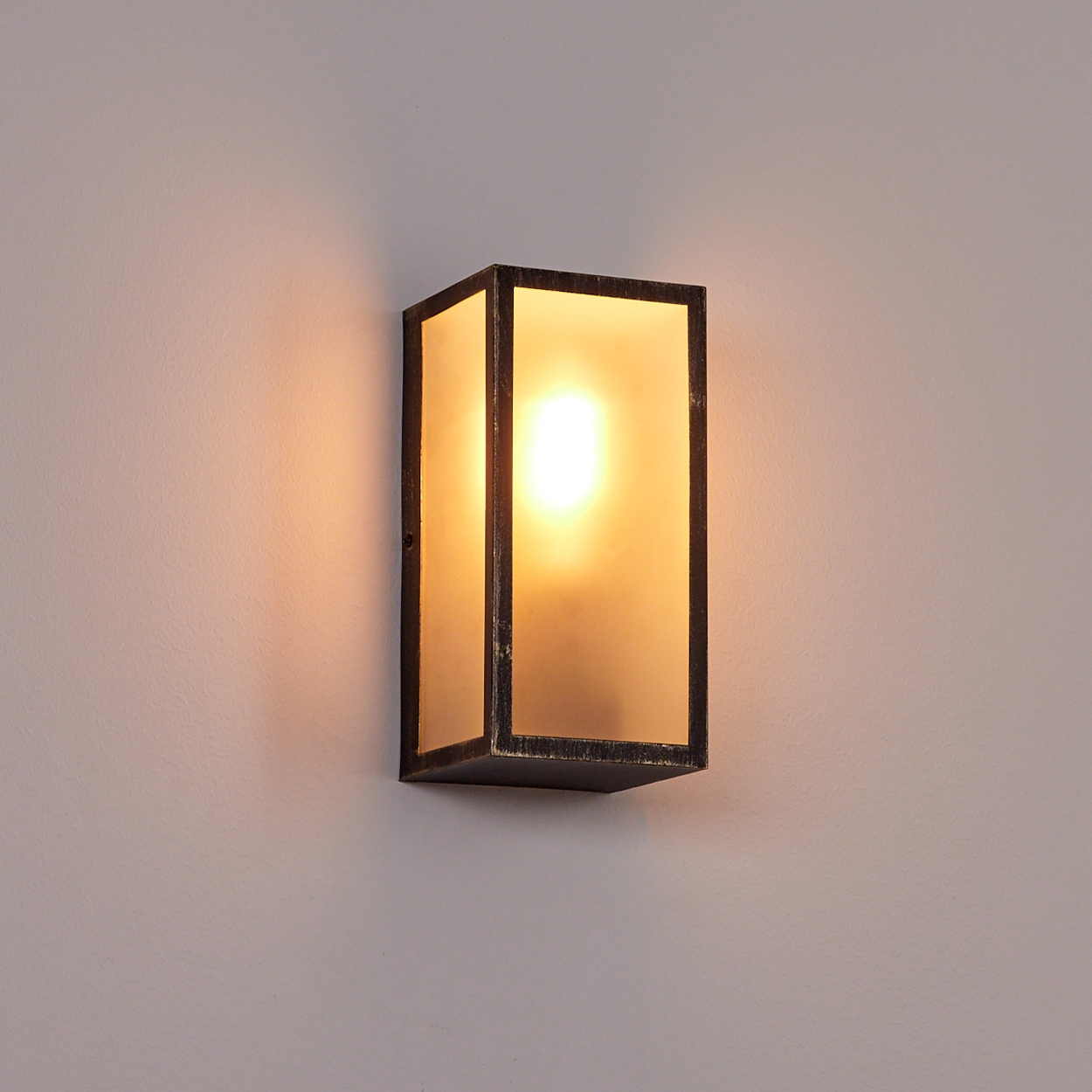Eine rechteckige Wandleuchte mit Milchglas und dunklem Rahmen.