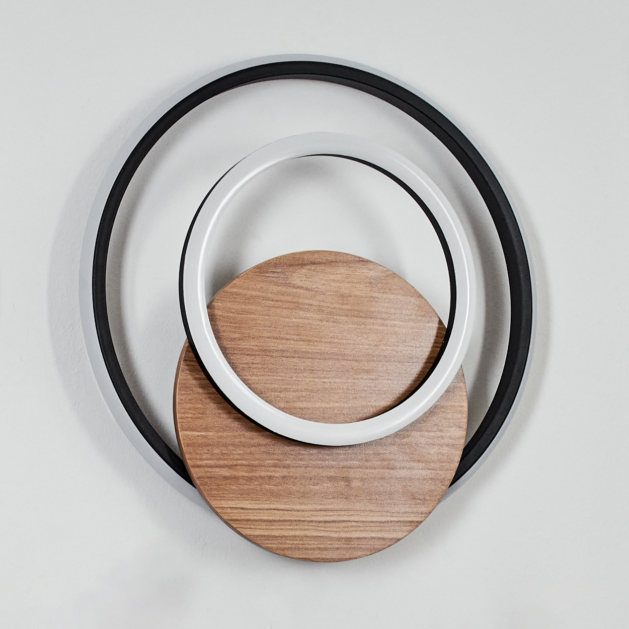 Eine Wandleuchte mit drei konzentrischen Ringen und einem Holz-Kreis.