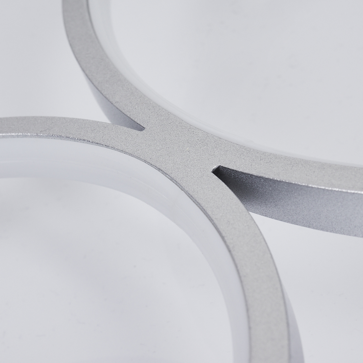 Nahaufnahme einer weißen und silbernen Deckenleuchte. Das Design ist kreisförmig und elegant.
