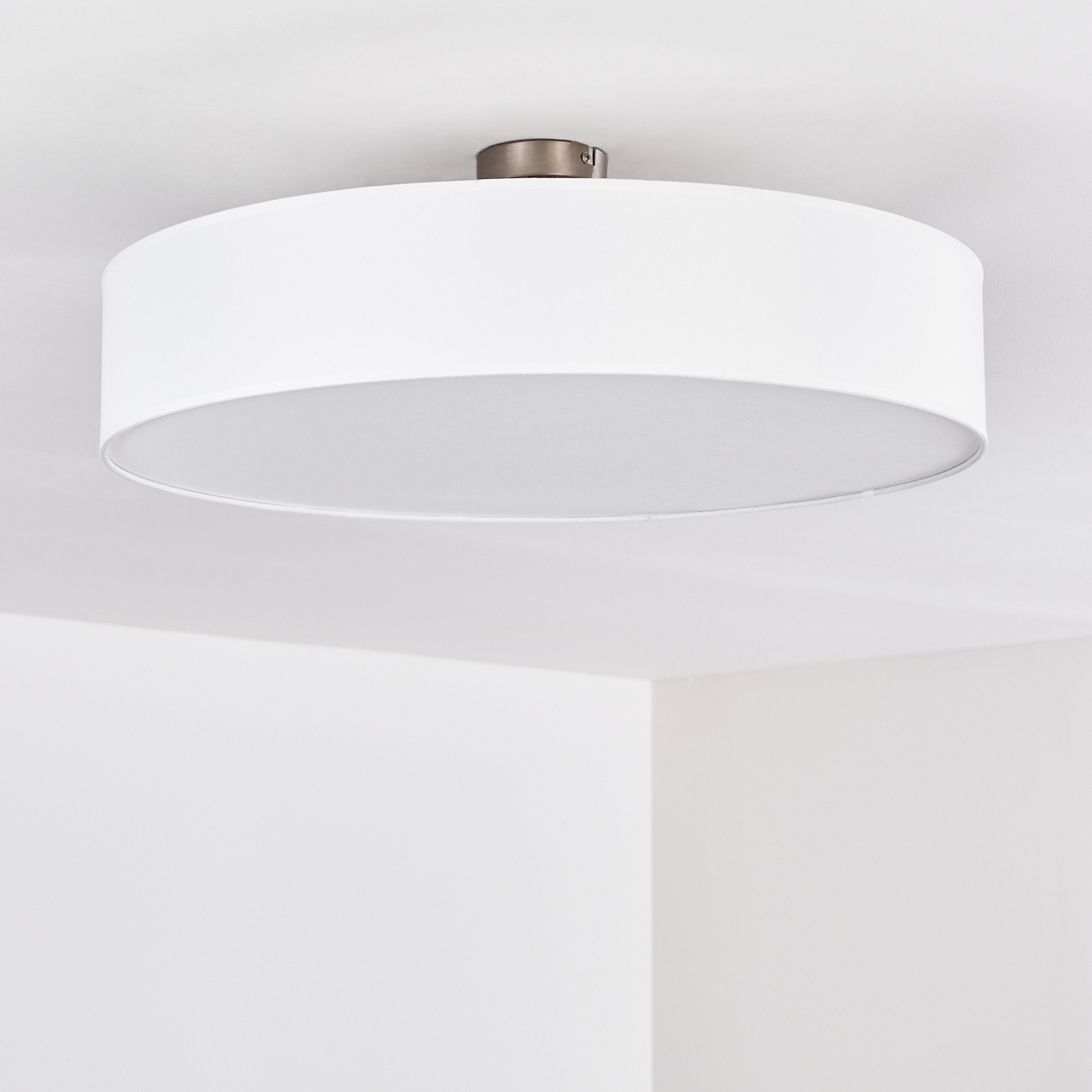 Eine weiße, kreisförmige Deckenlampe ist an der Decke befestigt.