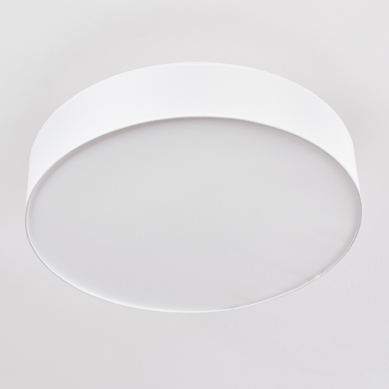 Eine weiße, runde Deckenleuchte ist an einer weißen Decke montiert und bietet ein schlichtes, modernes Design.