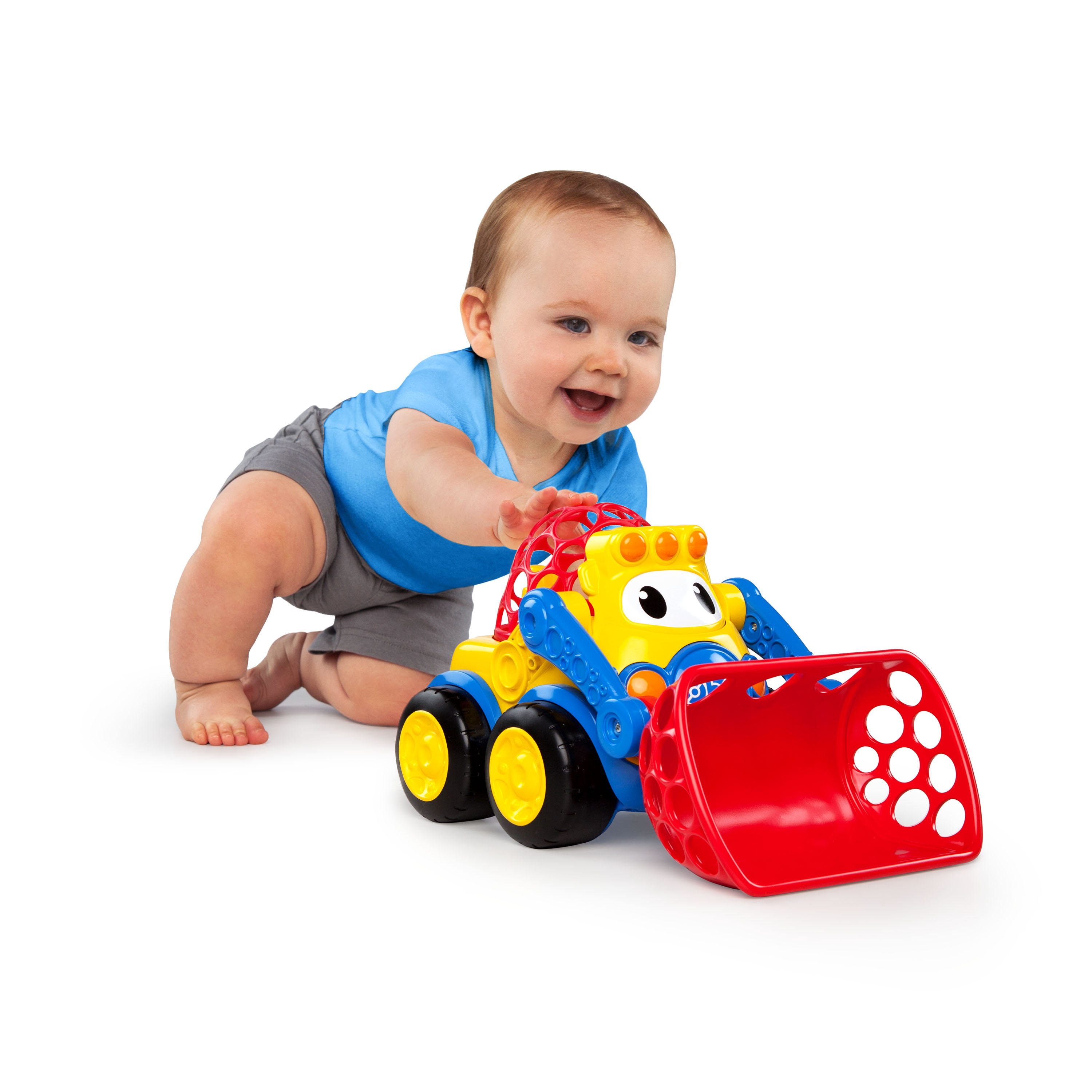 Un bebé con una camisa azul juega con un tractor de juguete rojo y amarillo. El bebé sonríe y busca el juguete.