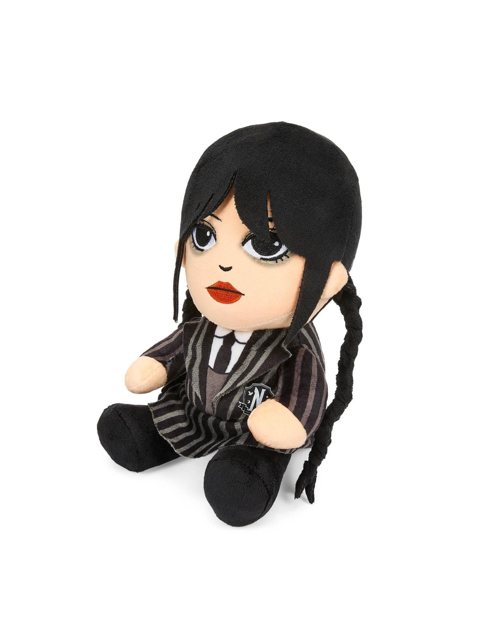 Eine Plüschpuppe von Wednesday Addams in einem schwarz-weiß gestreiften Anzug. Sie hat schwarze Zöpfe und einen neutralen Ausdruck.