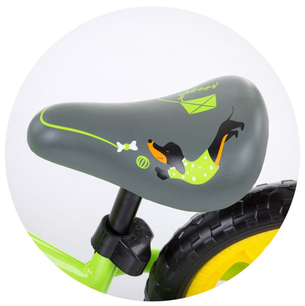 Primer plano del asiento de una bicicleta de equilibrio. El asiento es gris con un diseño de perro y fondo verde.