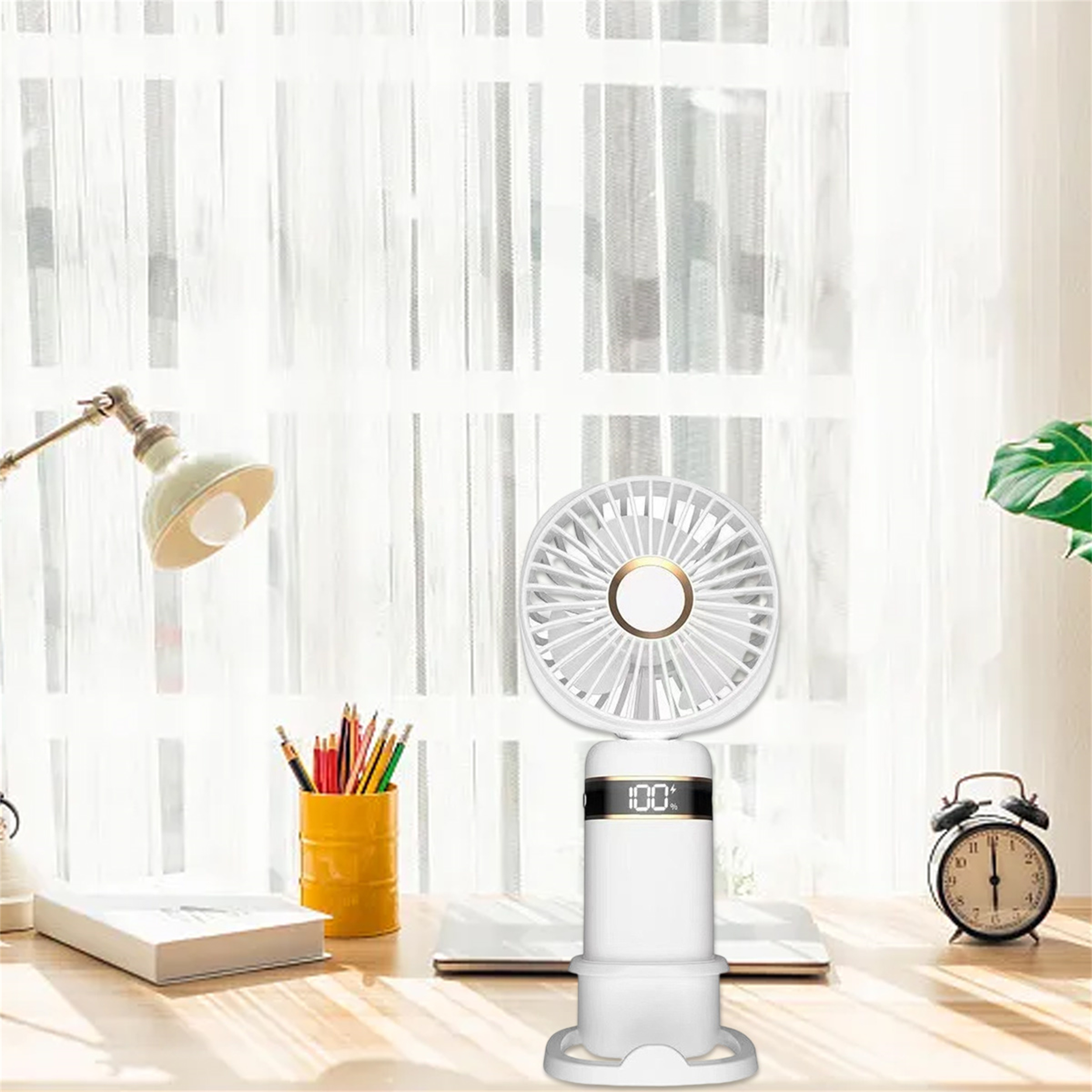 Ein weißer tragbarer Ventilator auf einem Schreibtisch mit Bleistiften, einer Lampe und einer Uhr im Hintergrund.