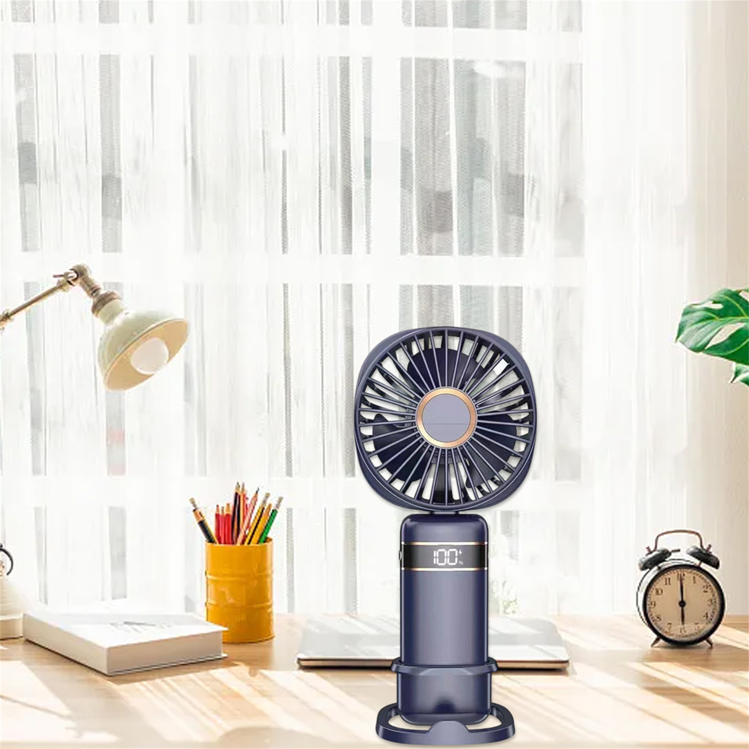 Ein kleiner, blauer Ventilator mit Digitalanzeige auf einem Schreibtisch mit Lampe, Stiften und Wecker.