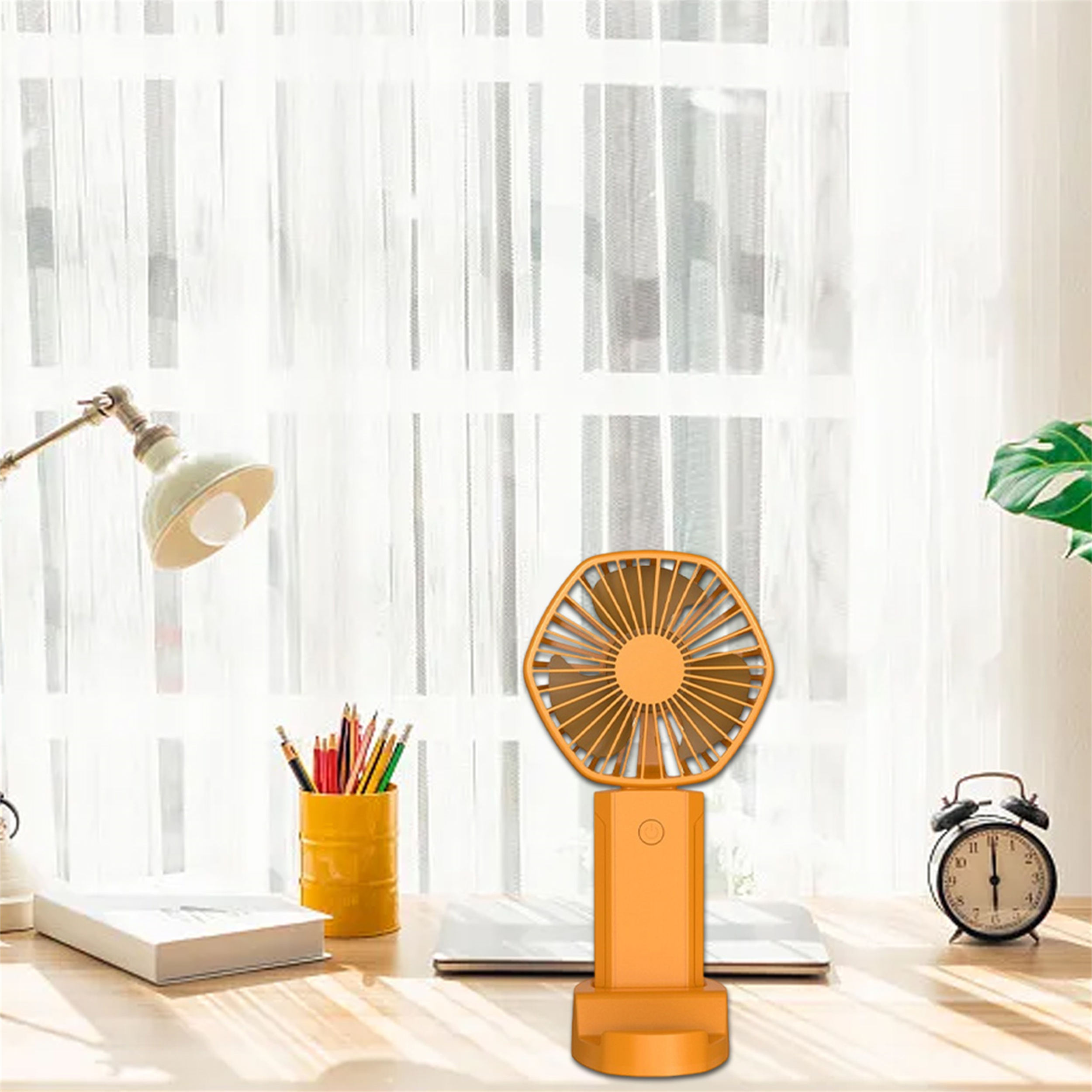 Ein orangefarbener Handventilator auf einem Schreibtisch. Der Ventilator ist dem Betrachter zugewandt.