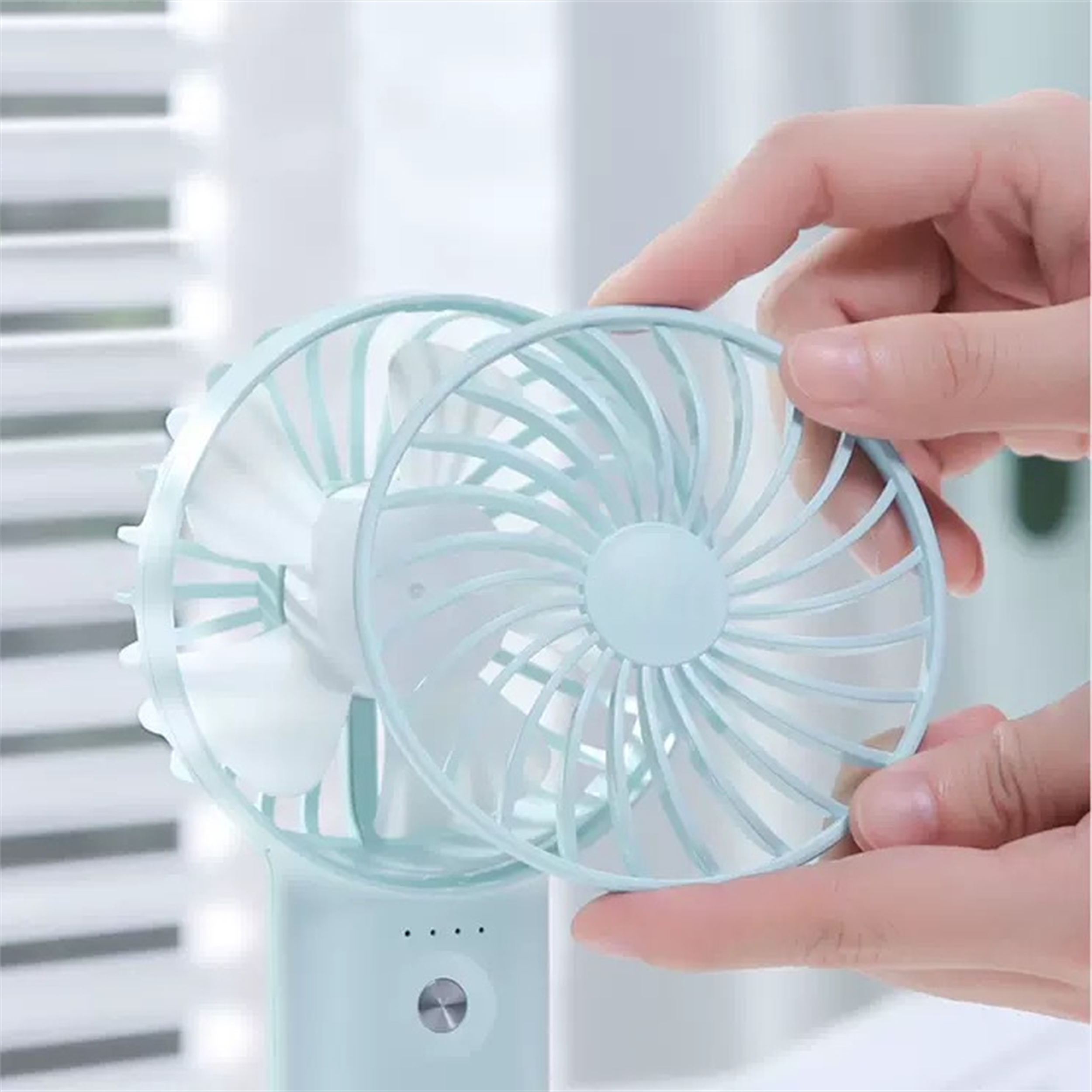 Eine Person montiert einen mintgrünen Handventilator.