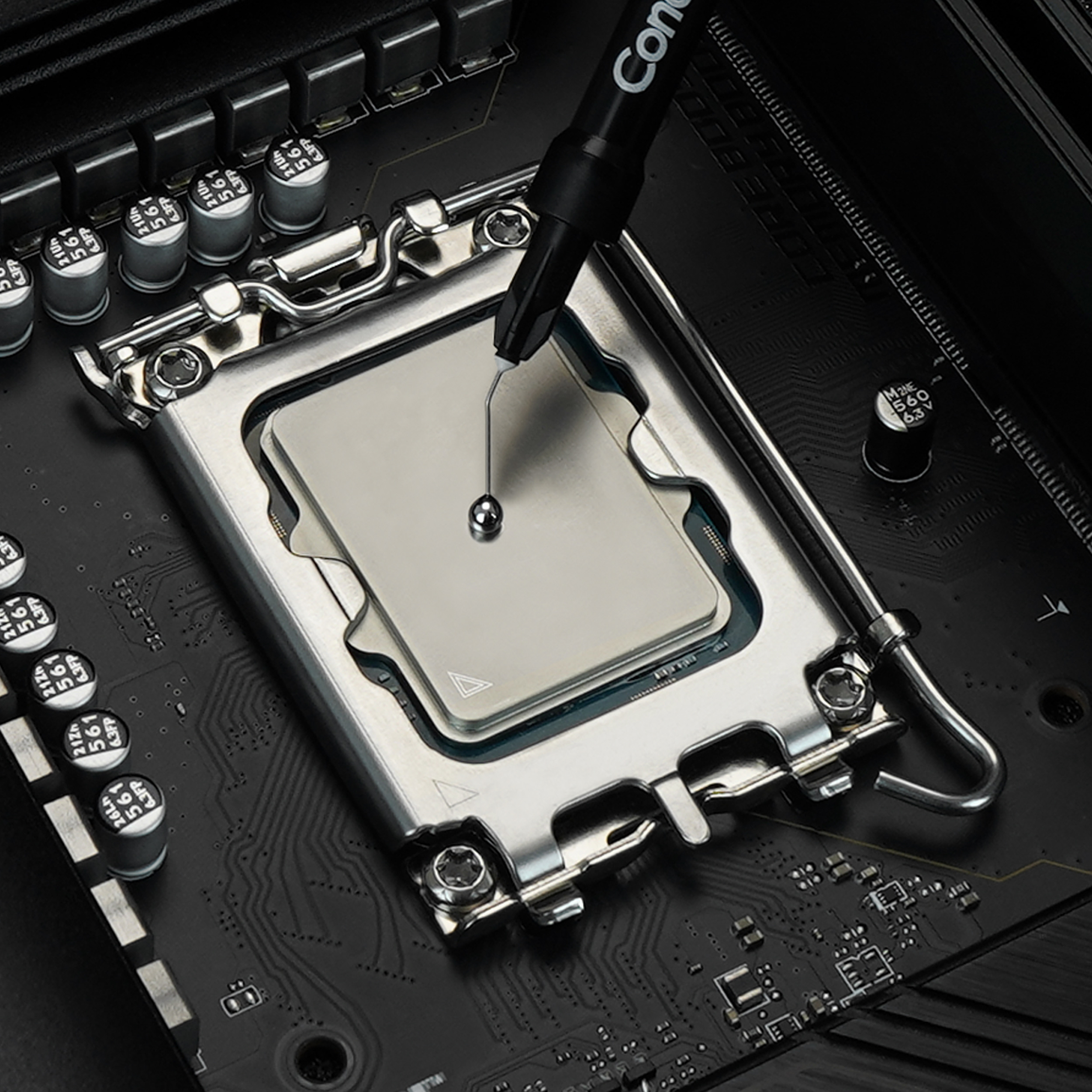 Eine CPU auf einem Motherboard, auf die mit einer Spritze Wärmeleitpaste aufgetragen wird.