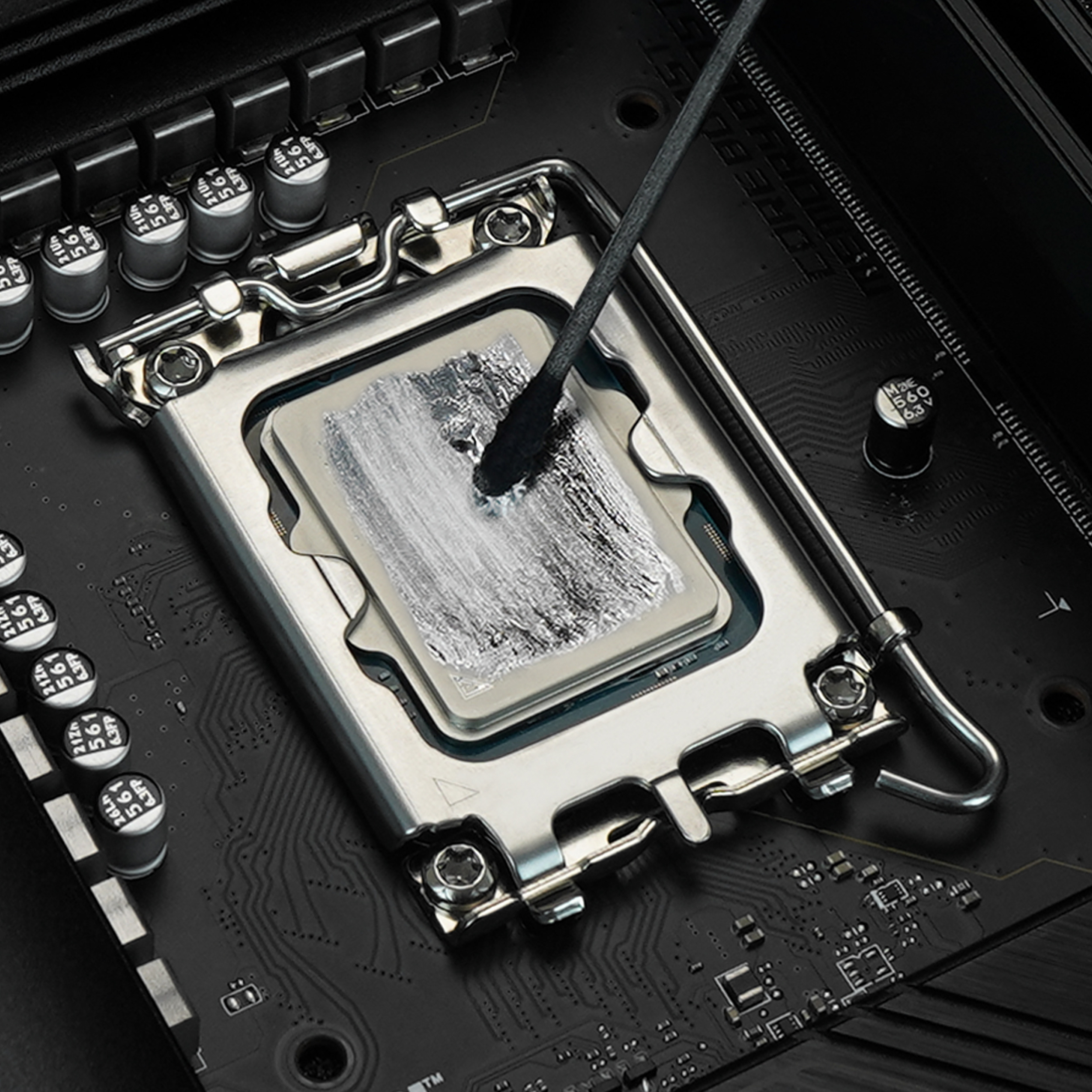 Termal macun uygulanmış bir CPU. Siyah bir aplikatör, macunu CPU'ya yayıyor. Arka plan bir anakart.