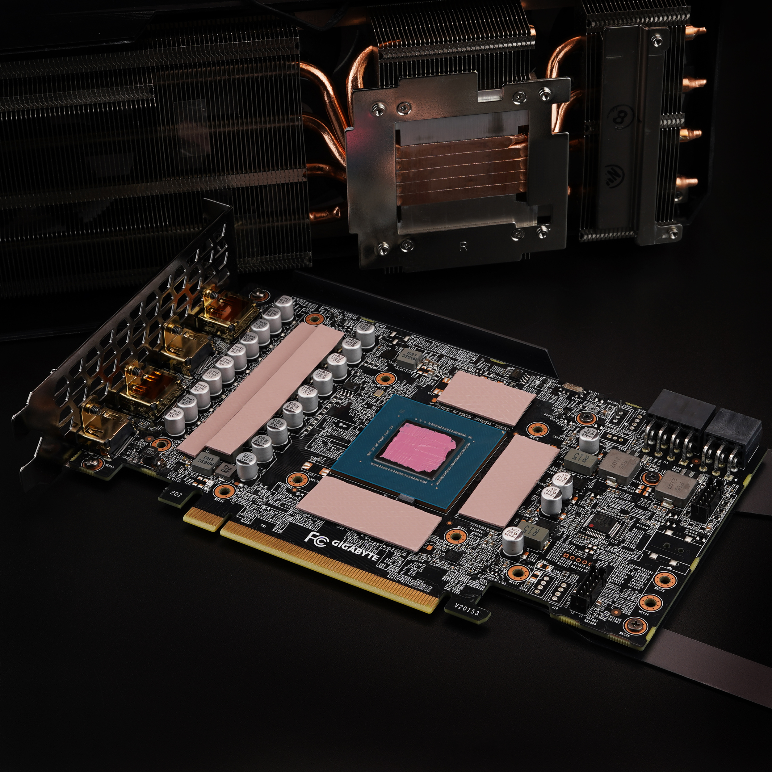 Una scheda grafica con dissipatori di calore e pad termici. Un dissipatore CPU sullo sfondo.