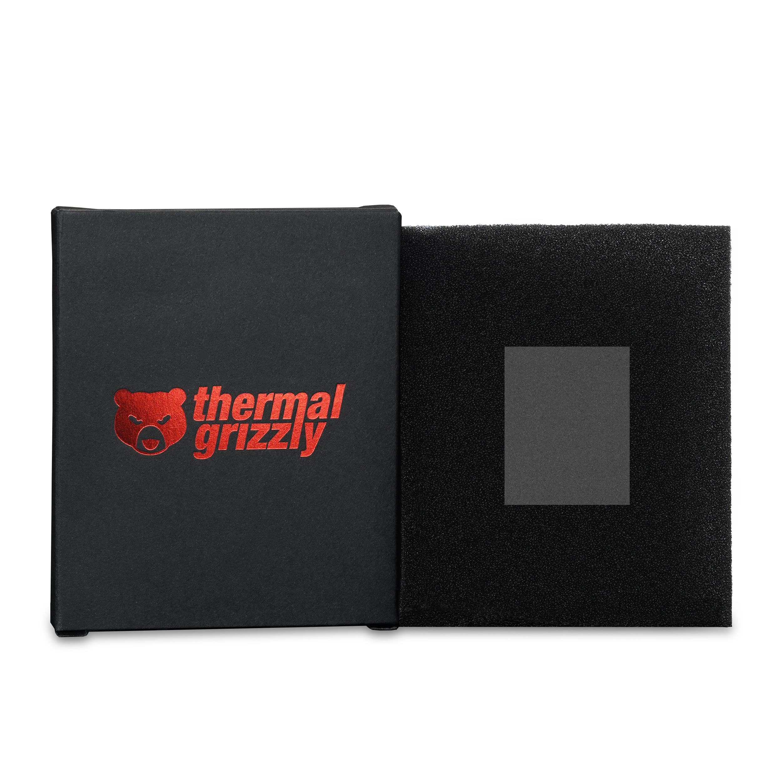 Boîte noire, avec logo d'ours rouge et texte 'thermal grizzly'. Boîte ouverte avec de la mousse noire à l'intérieur.