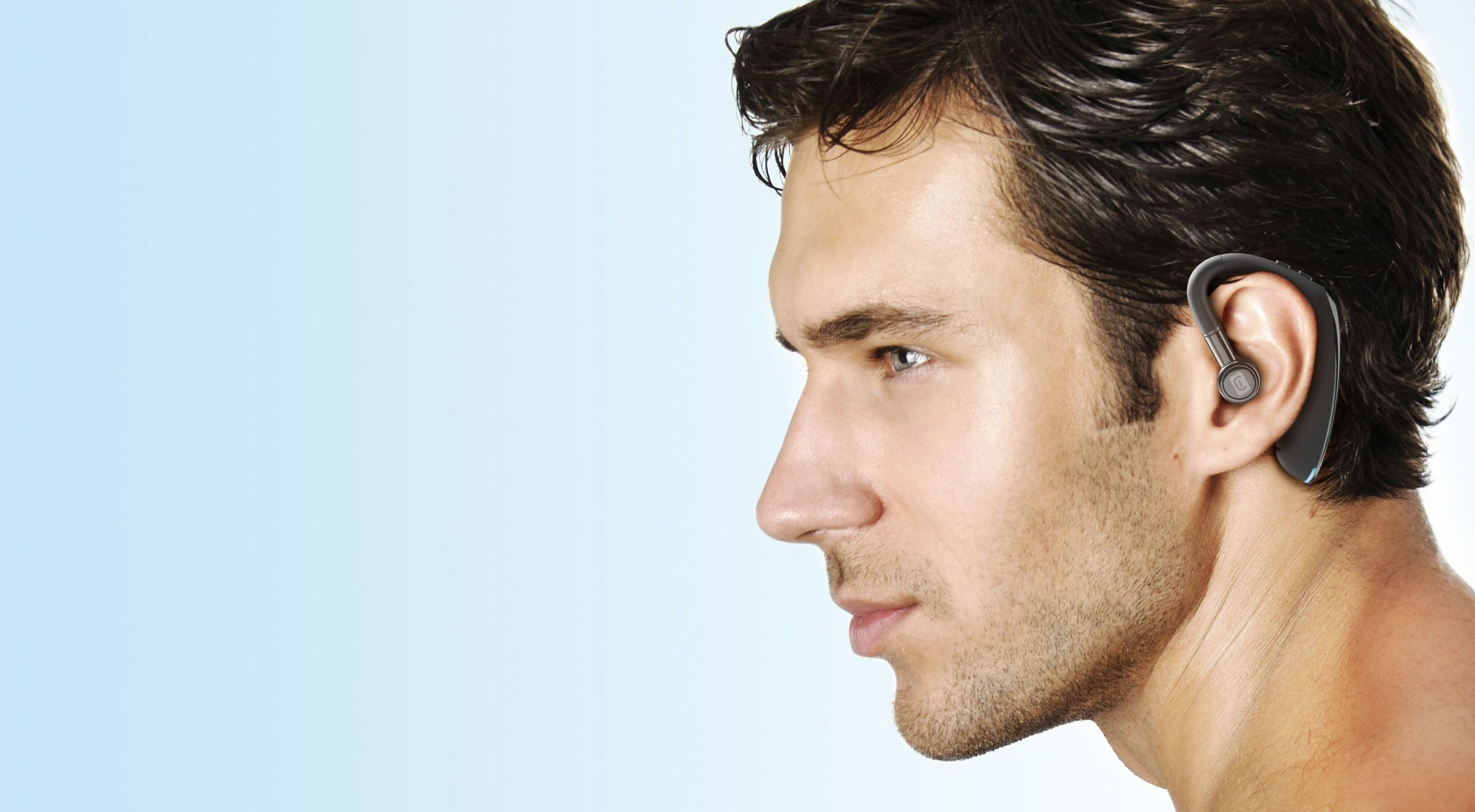 Un hombre con un auricular. Está mirando hacia la izquierda. El auricular es negro.