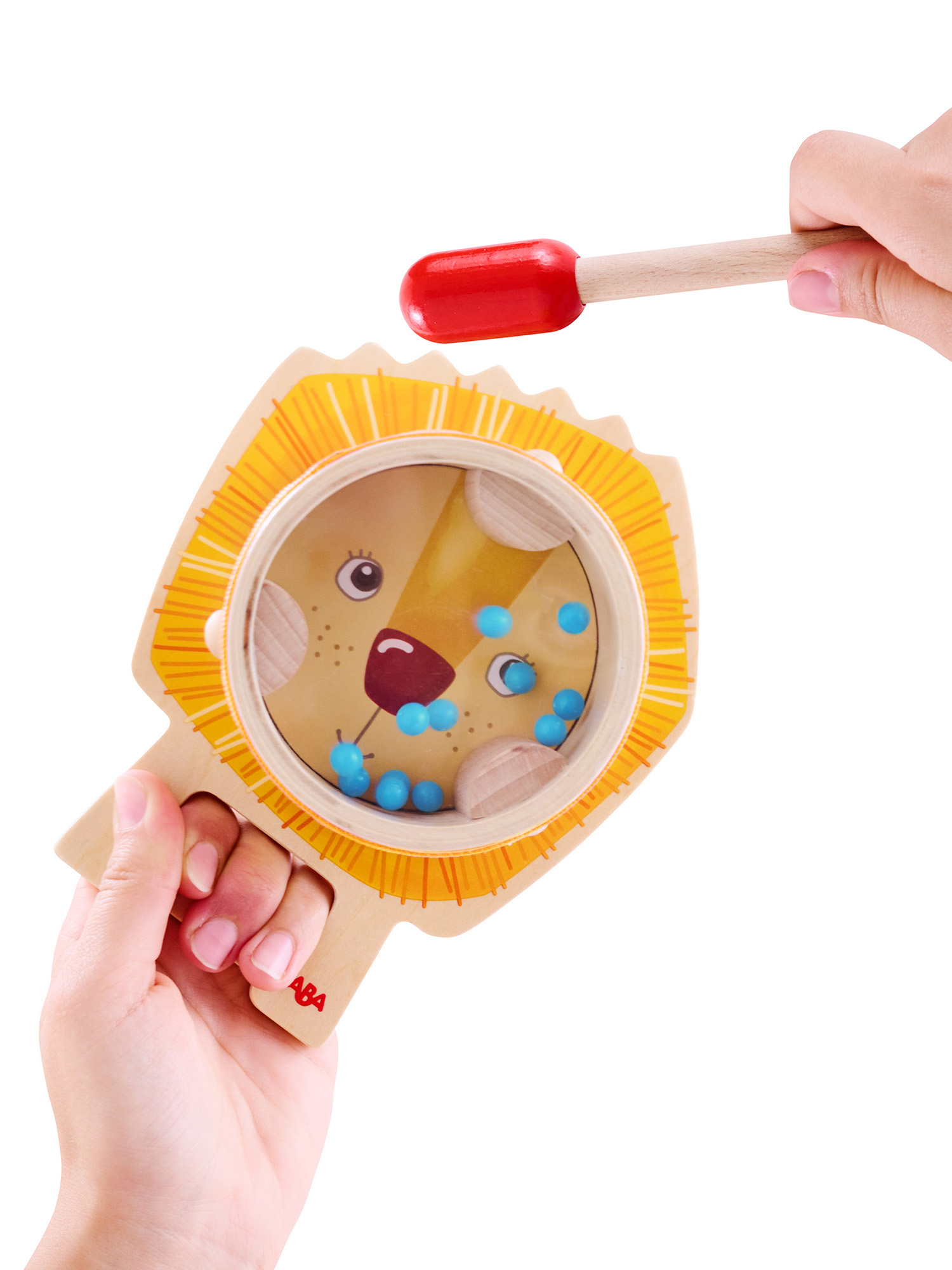 Person hält ein Rasselsspielzeug mit Löwengesicht, blauen Perlen im Inneren und einem Trommelschlägel mit roter Spitze.